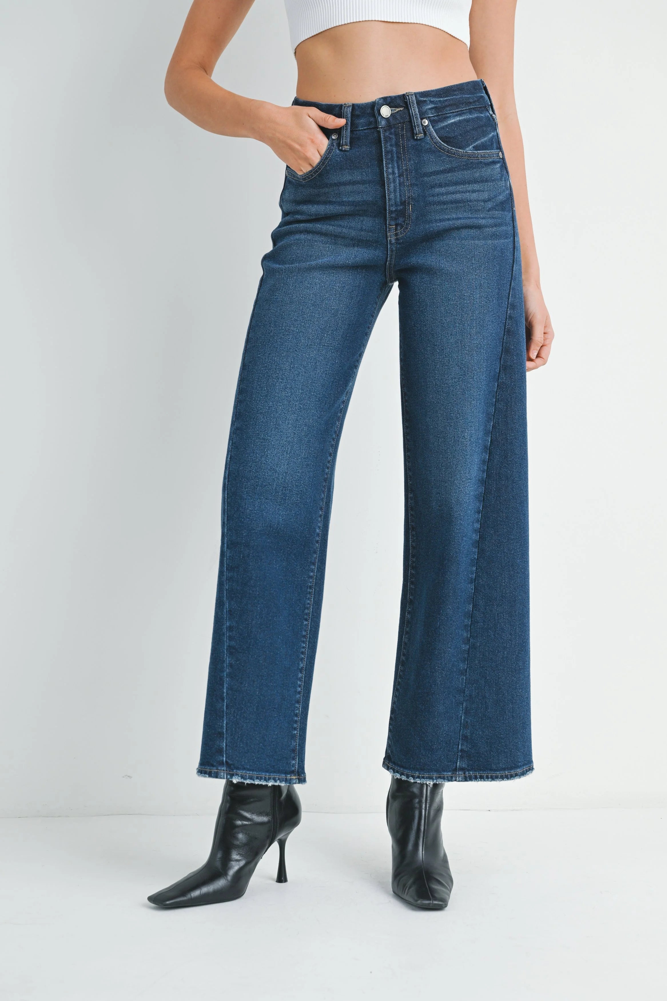 Woman wearing blue jeans and a white top on a white background