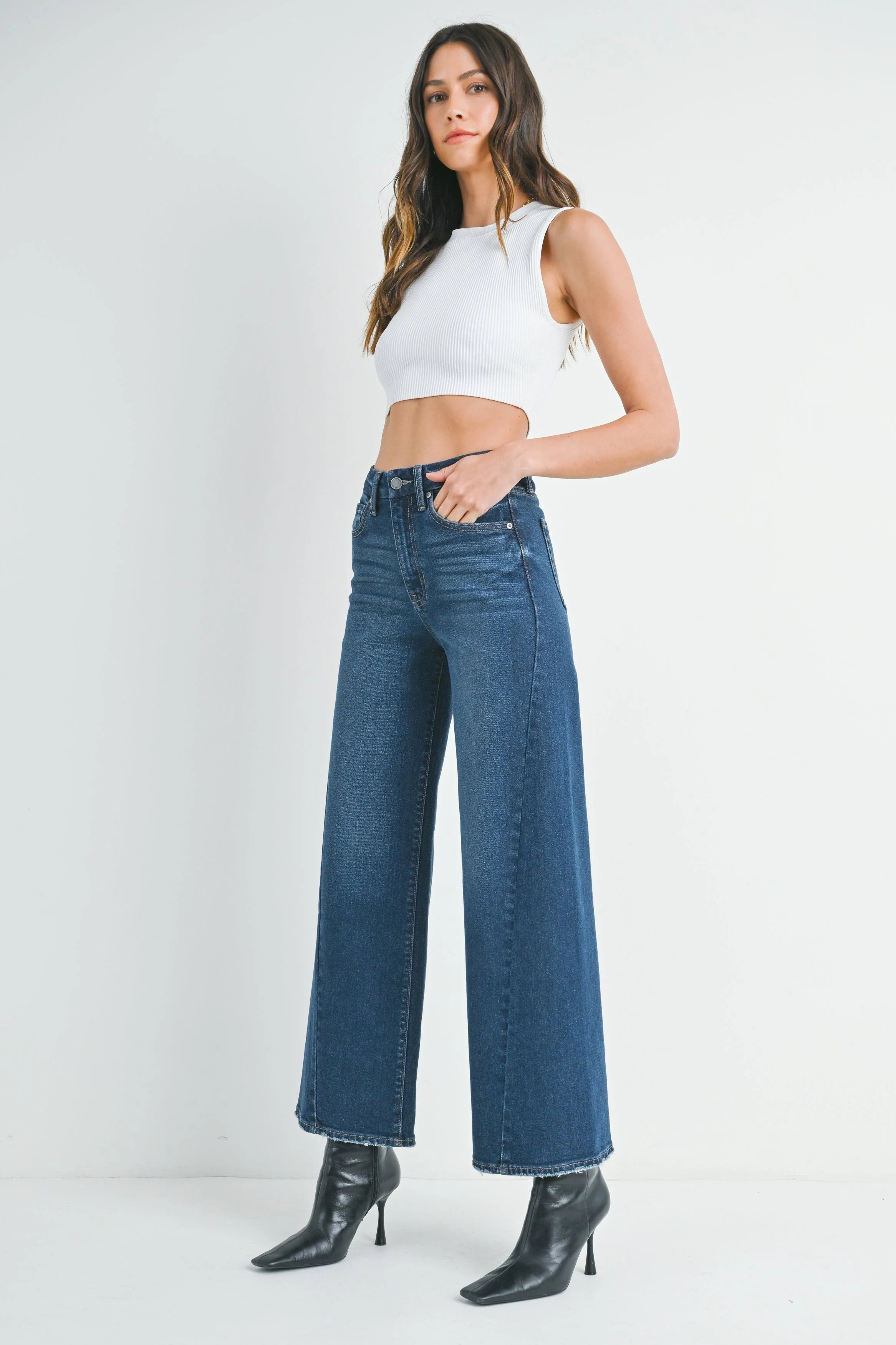 Woman wearing a white crop top and blue jeans on a white background