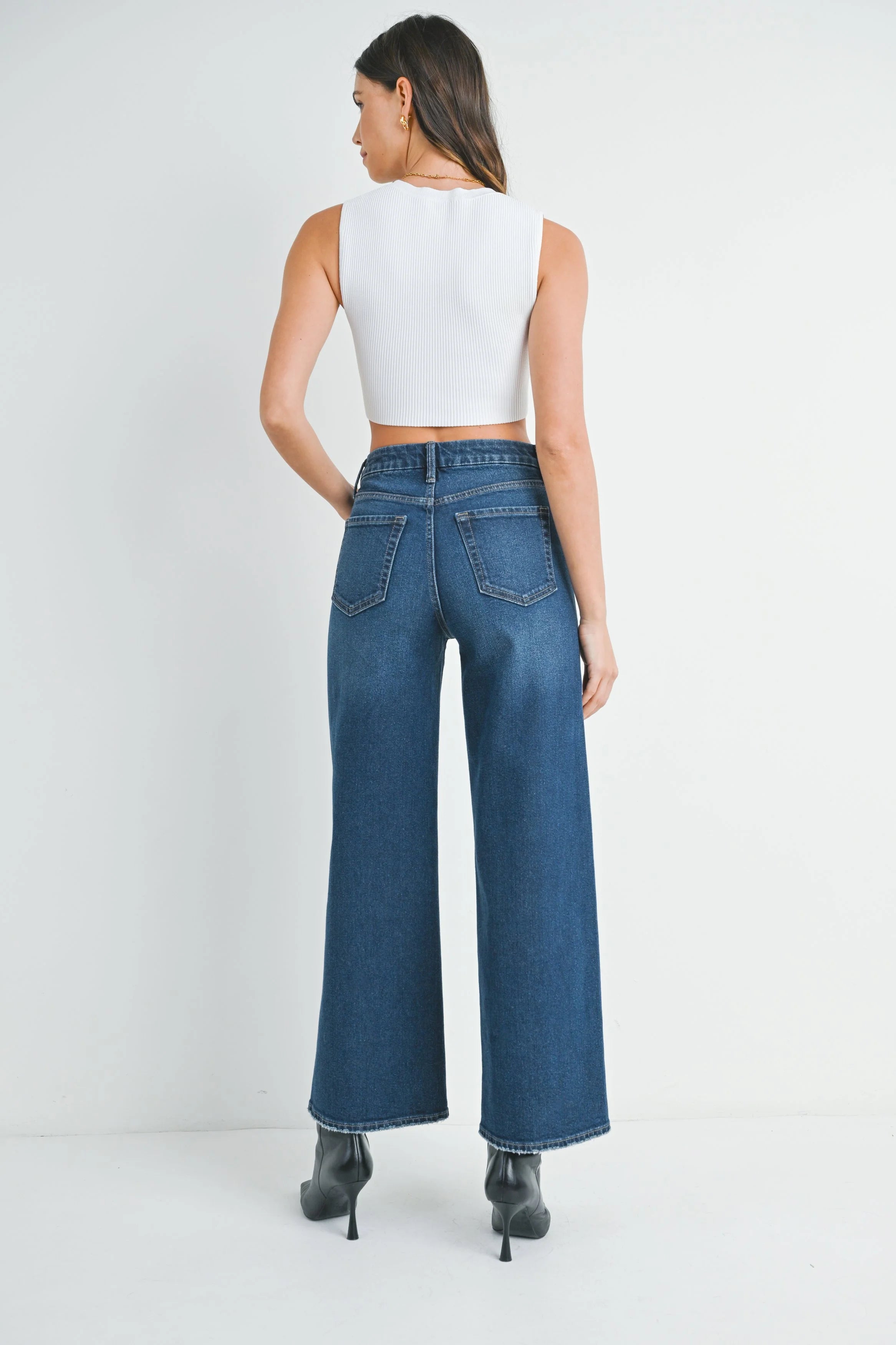 Woman wearing blue jeans and a white top on a white background