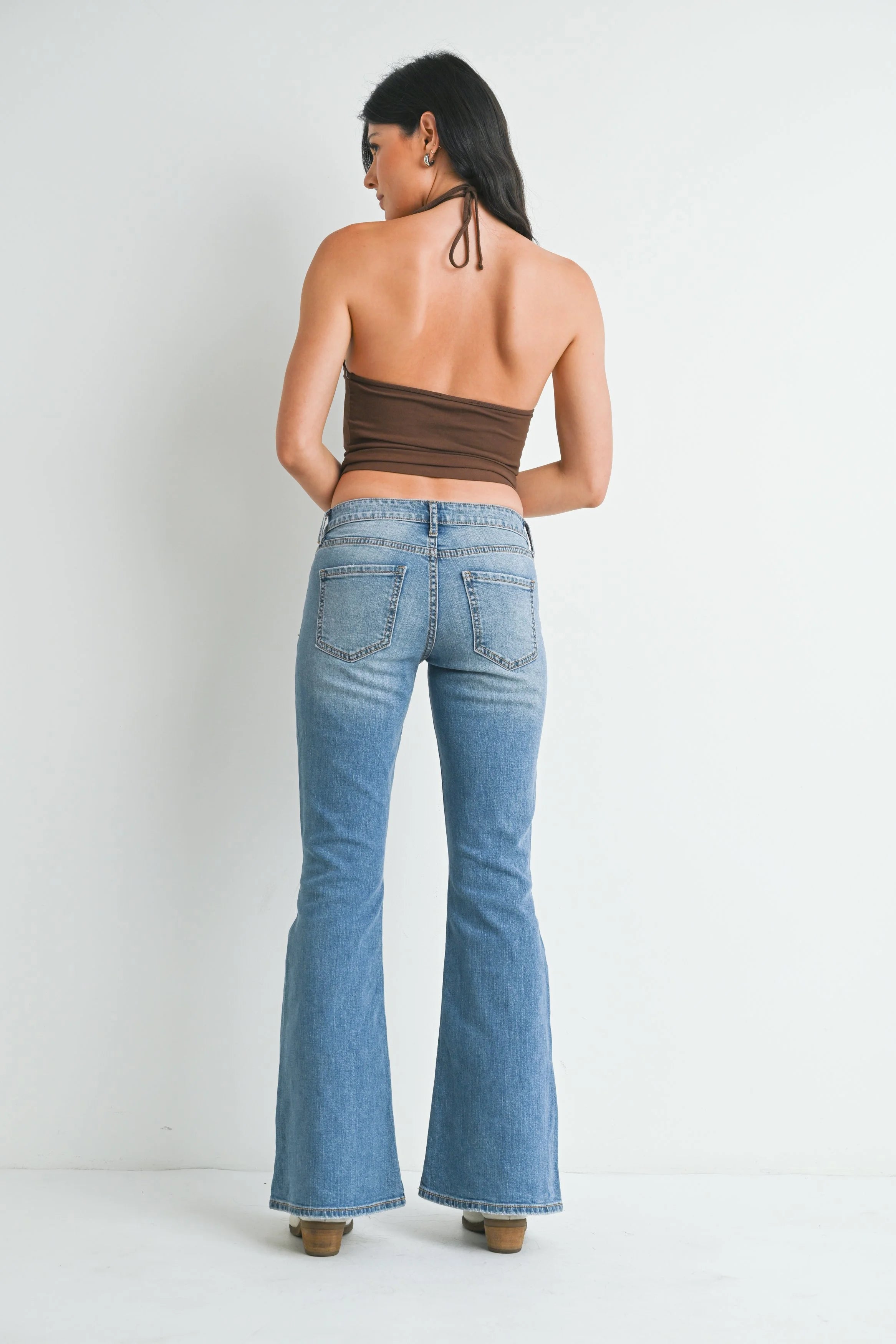 Woman wearing a strapless top and blue jeans on a white background