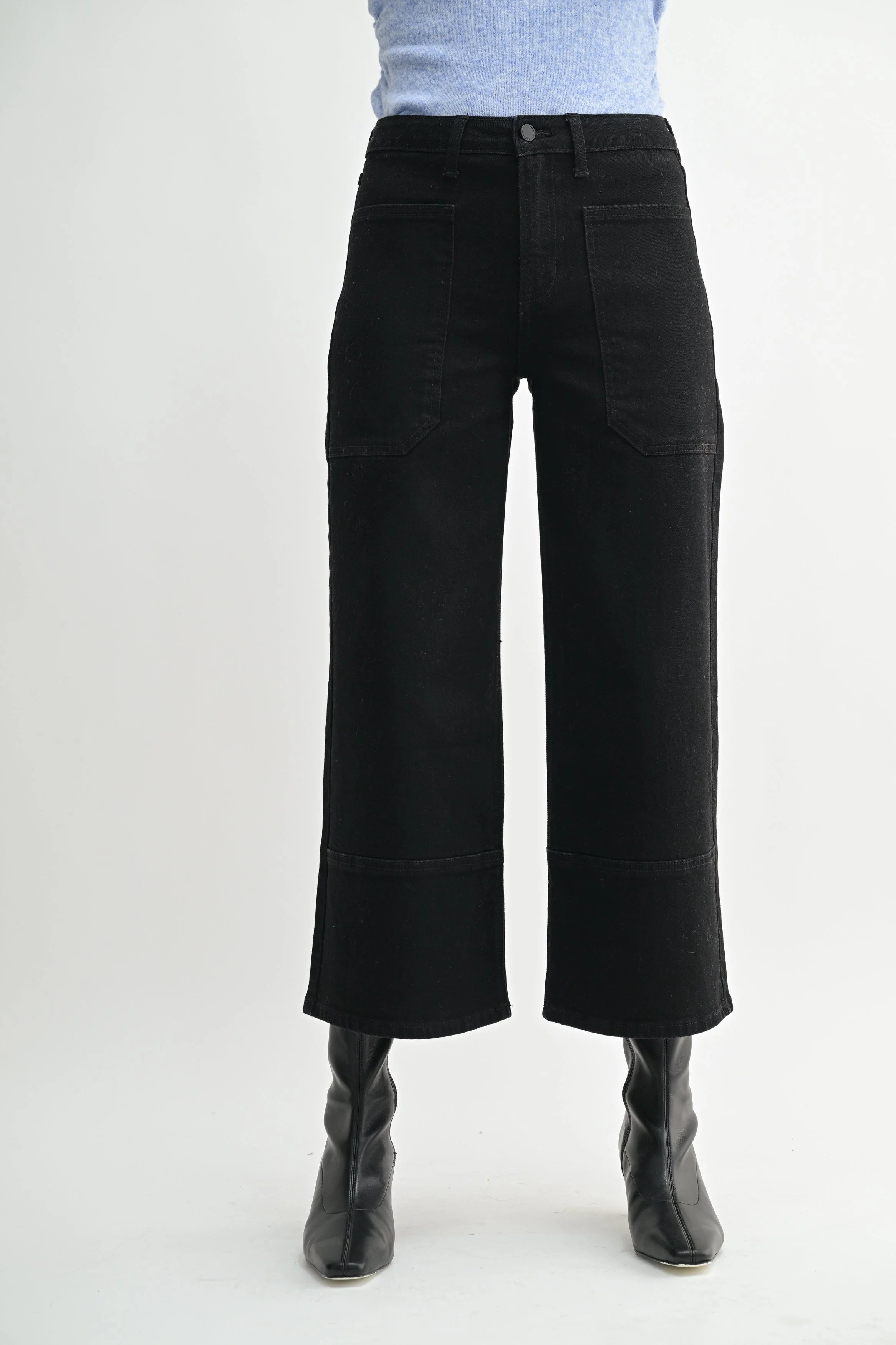 Person wearing black wide-leg jeans on a white background