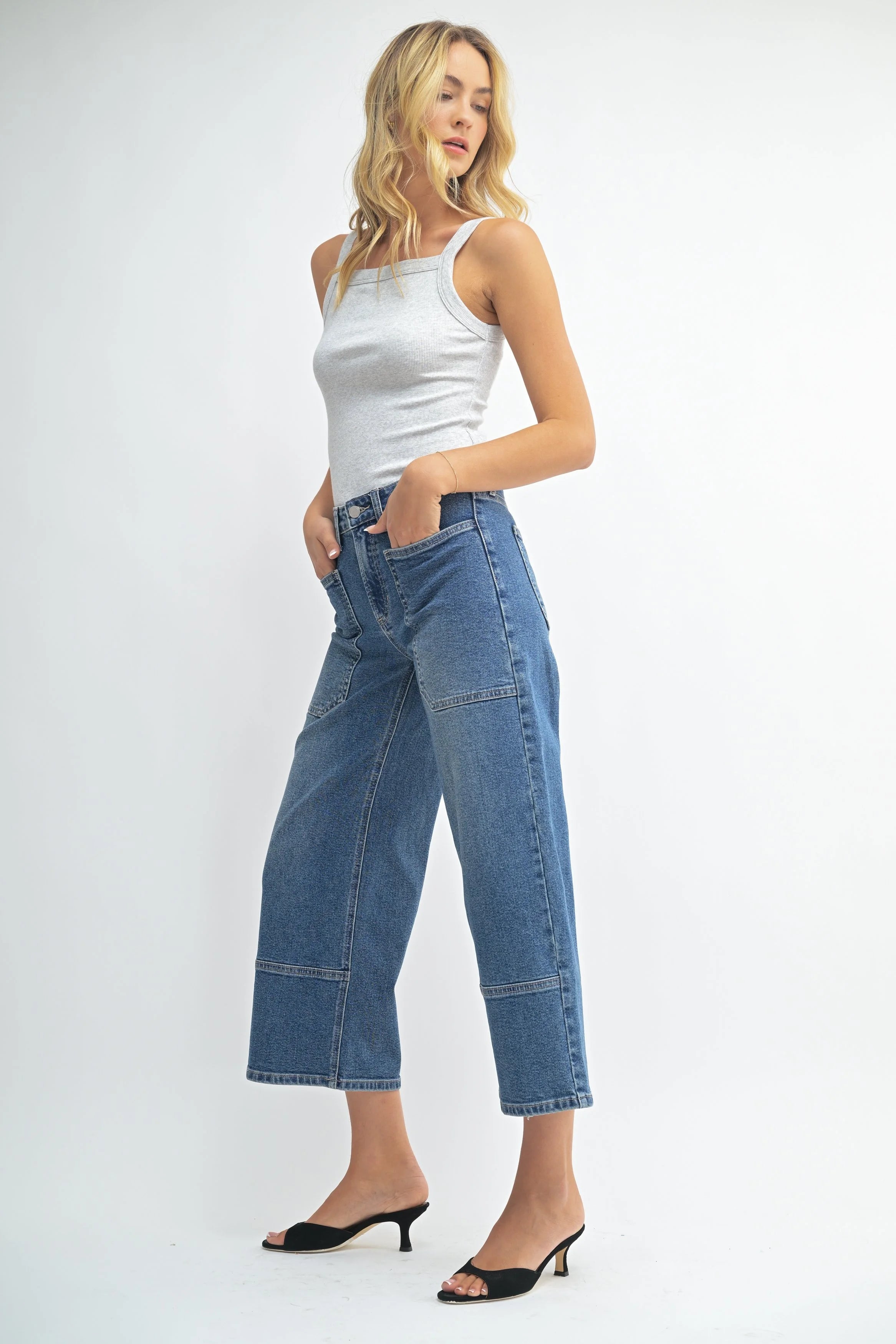 Woman wearing a white tank top and blue jeans on a white background