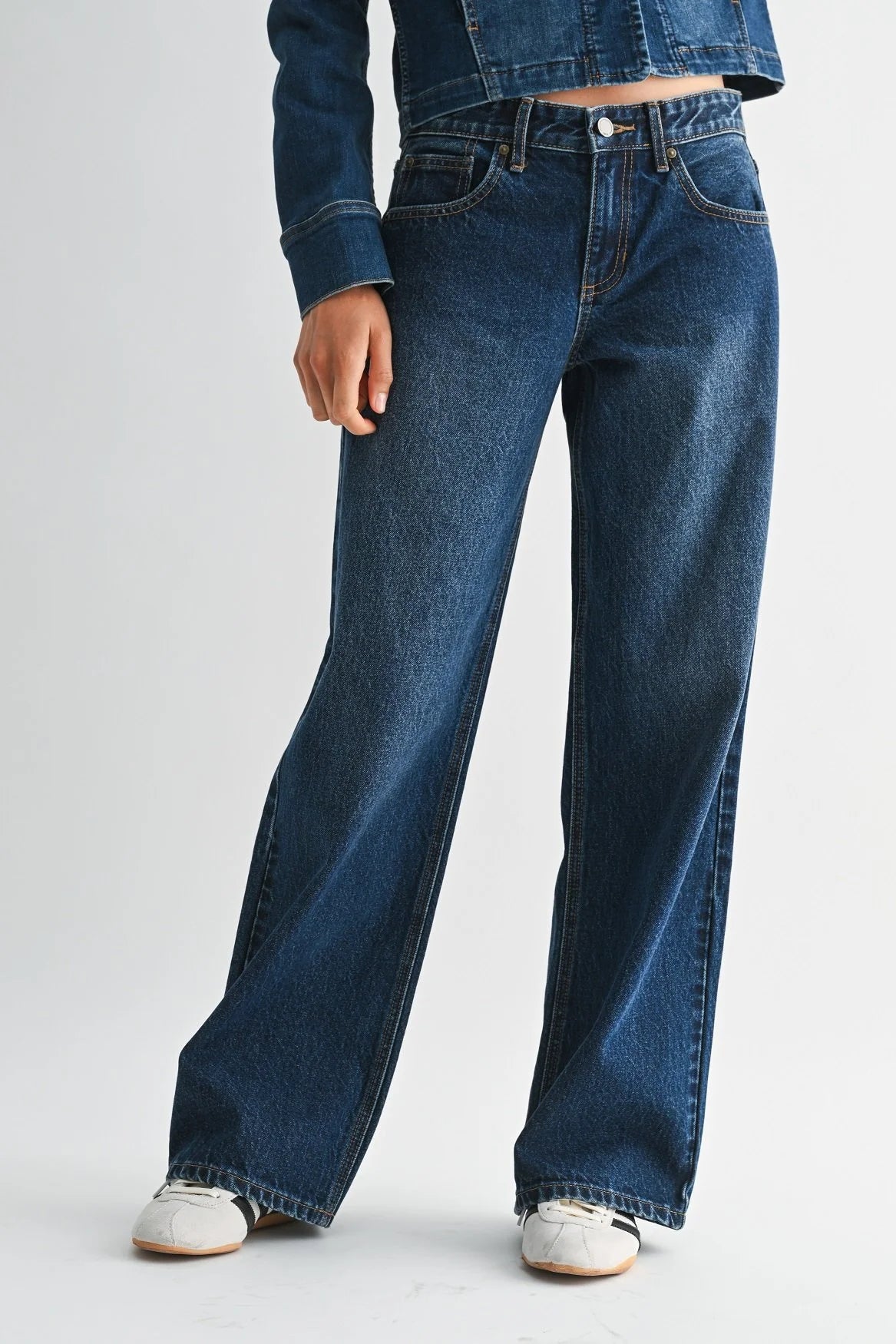 Woman modeling denim on a white background.