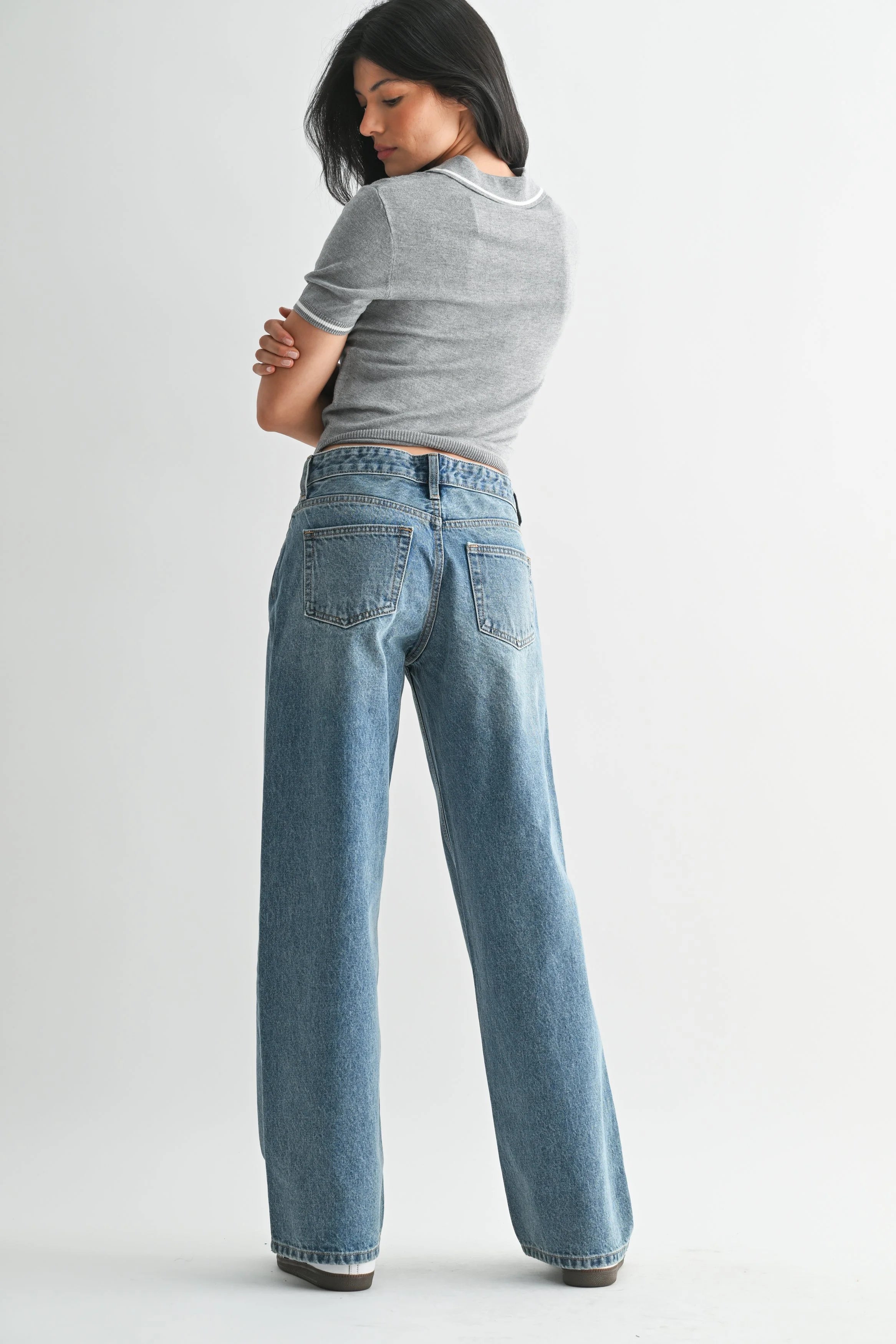 Woman wearing a gray t-shirt and blue jeans on a white background