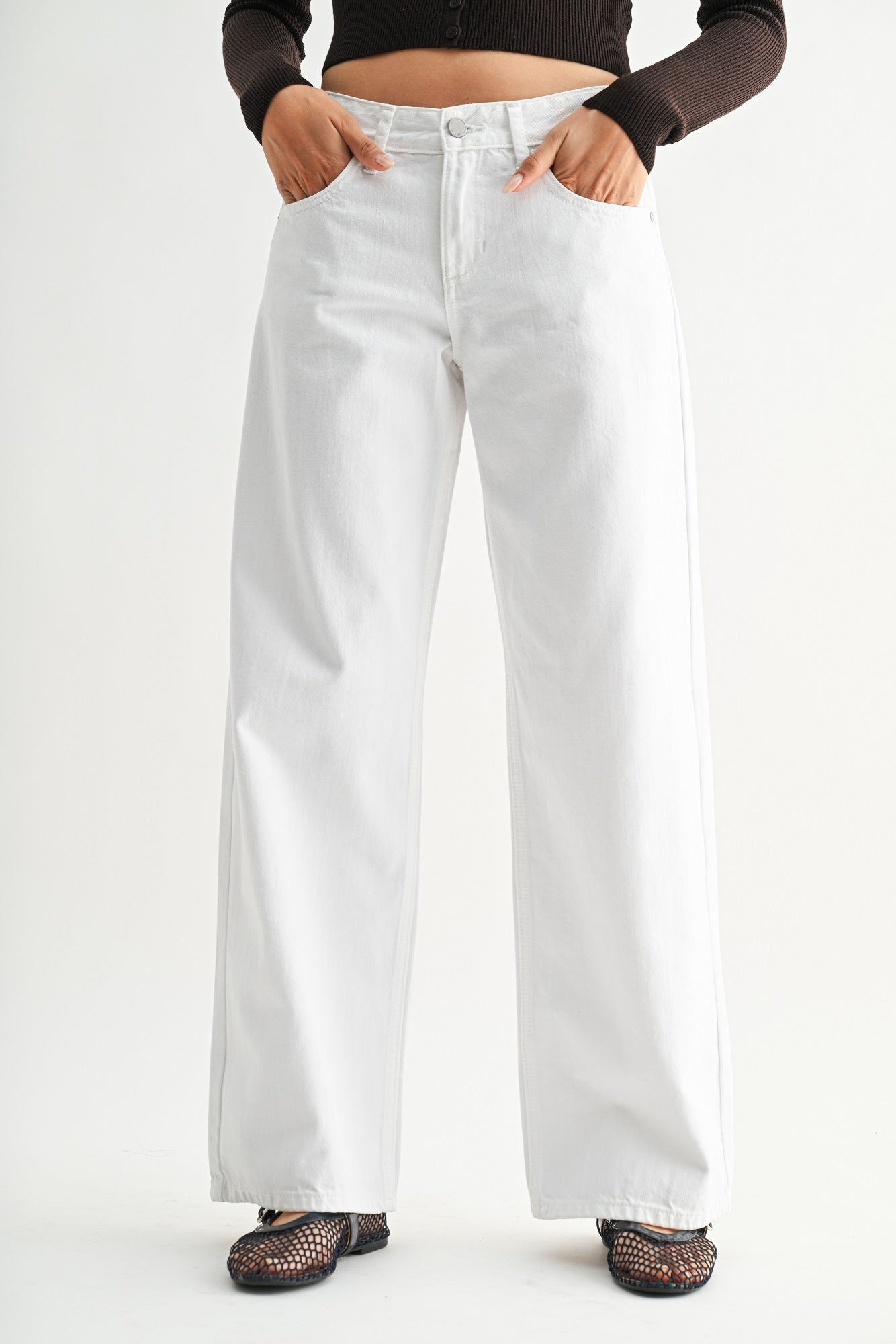 Person wearing white wide-leg jeans on a plain background