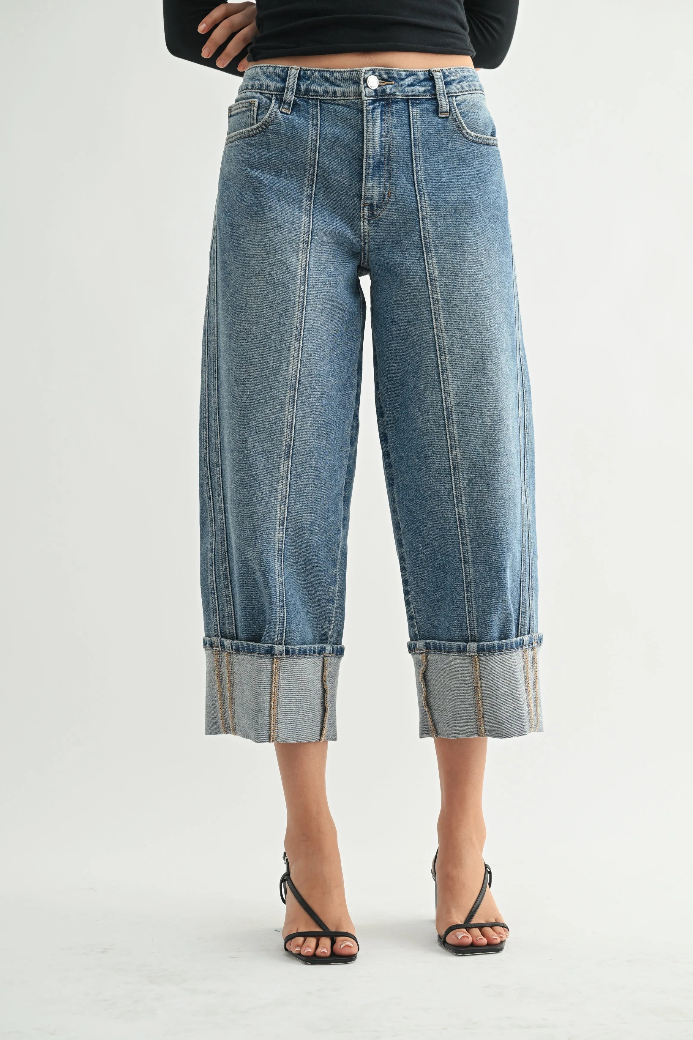 Cropped blue jeans worn by a person on a white background