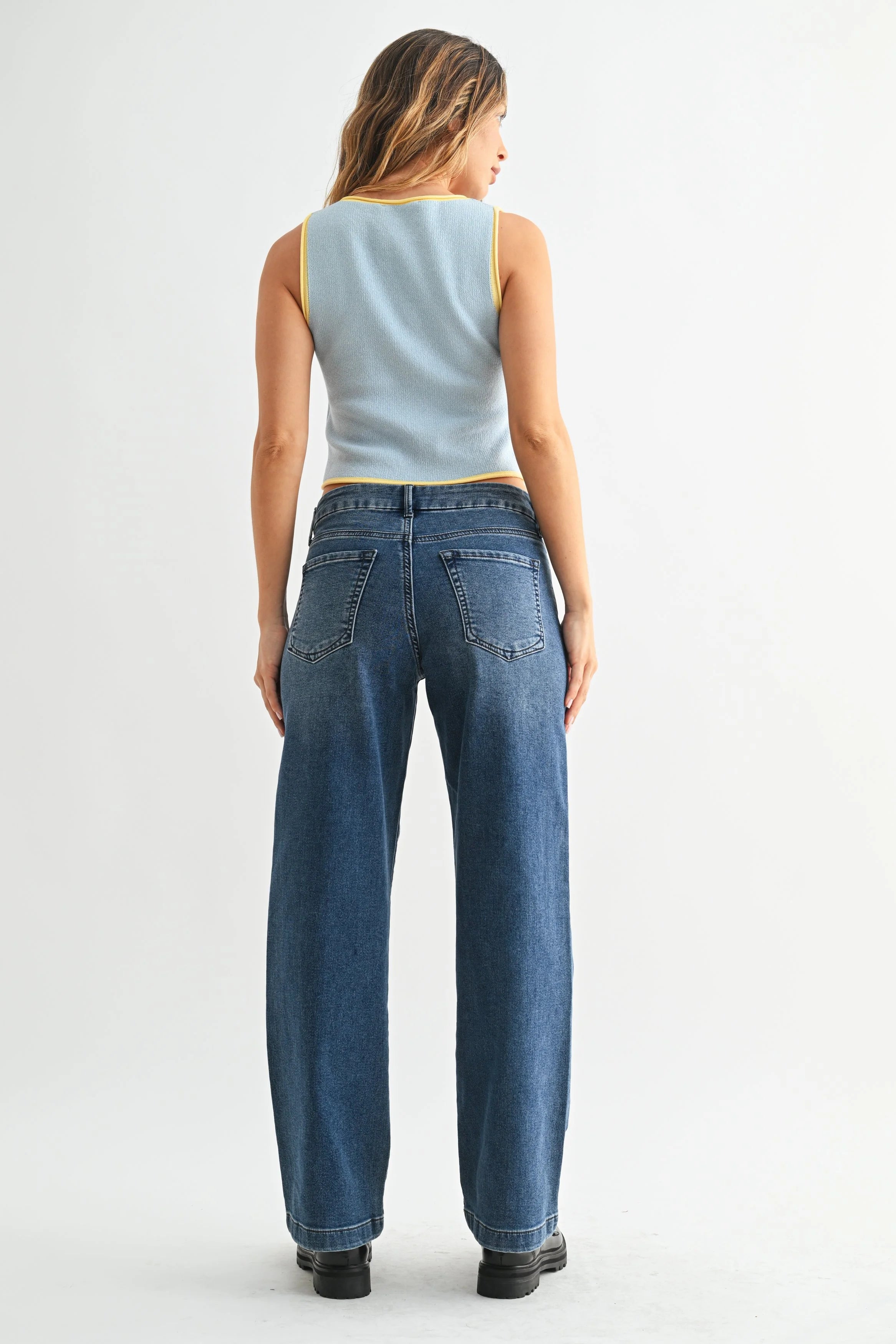 Woman wearing blue jeans and a light blue sleeveless top on a white background