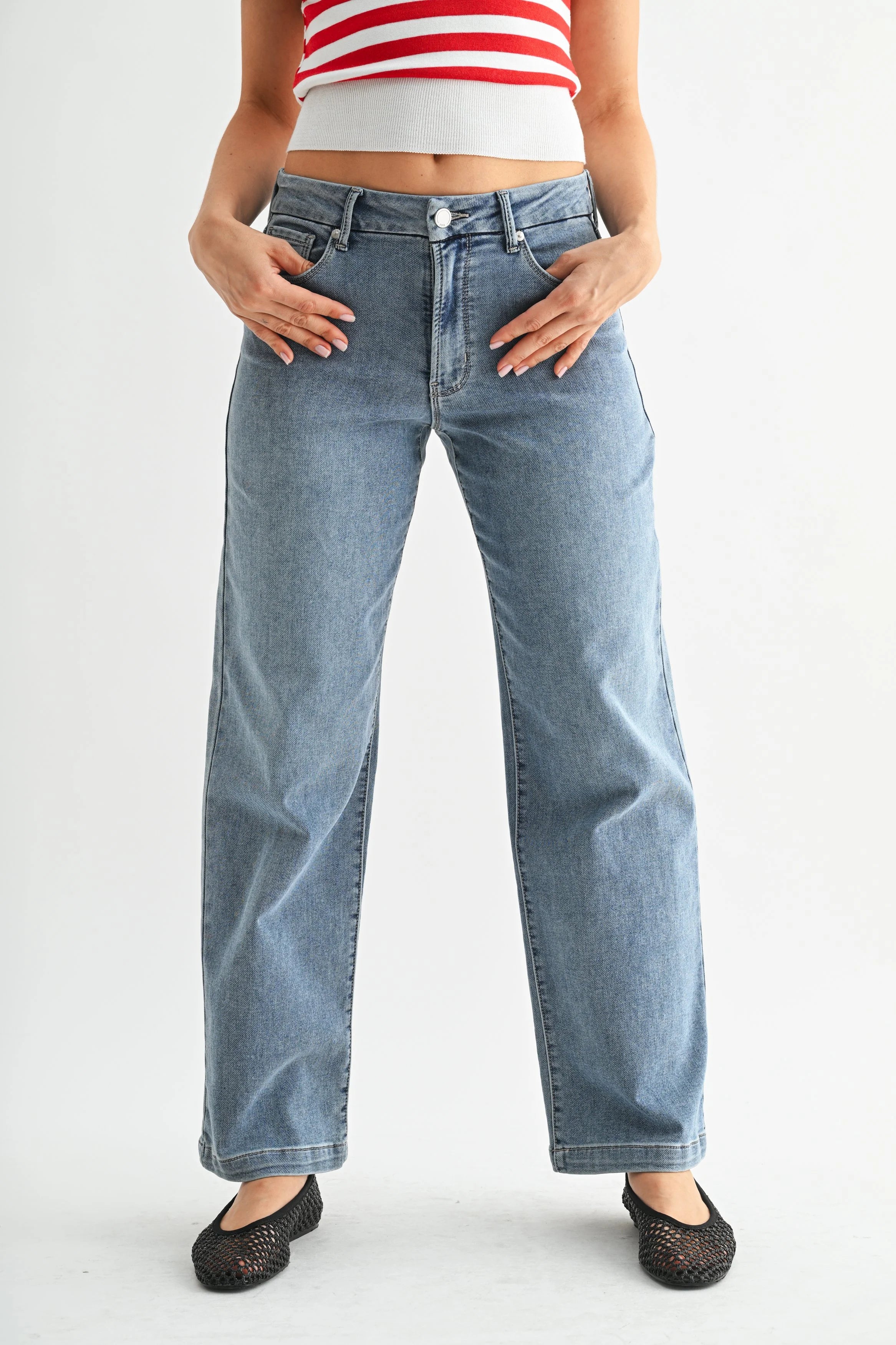 Person wearing light blue jeans and a red and white striped top on a plain background