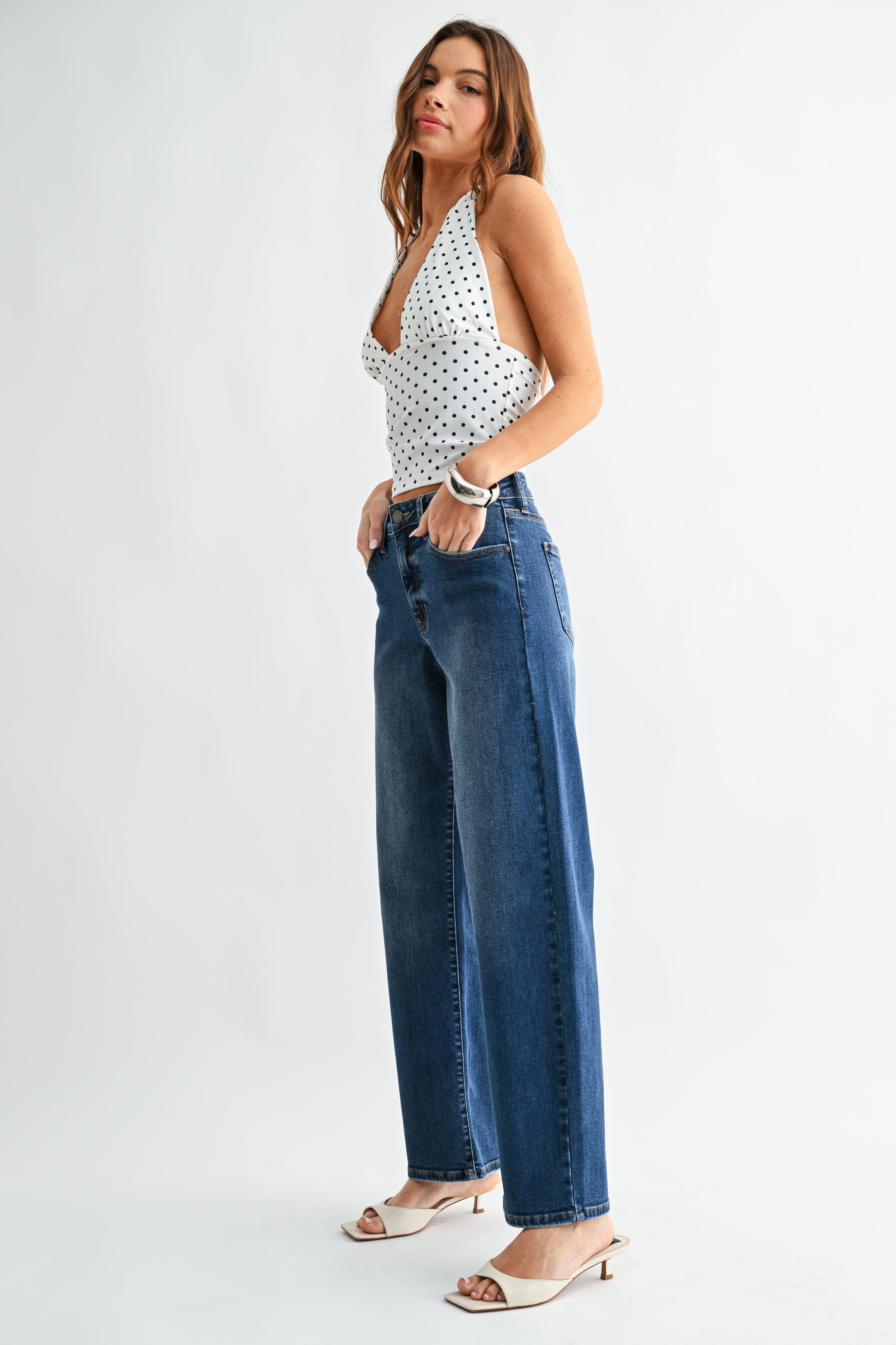 Woman wearing a polka dot top and blue jeans on a white background