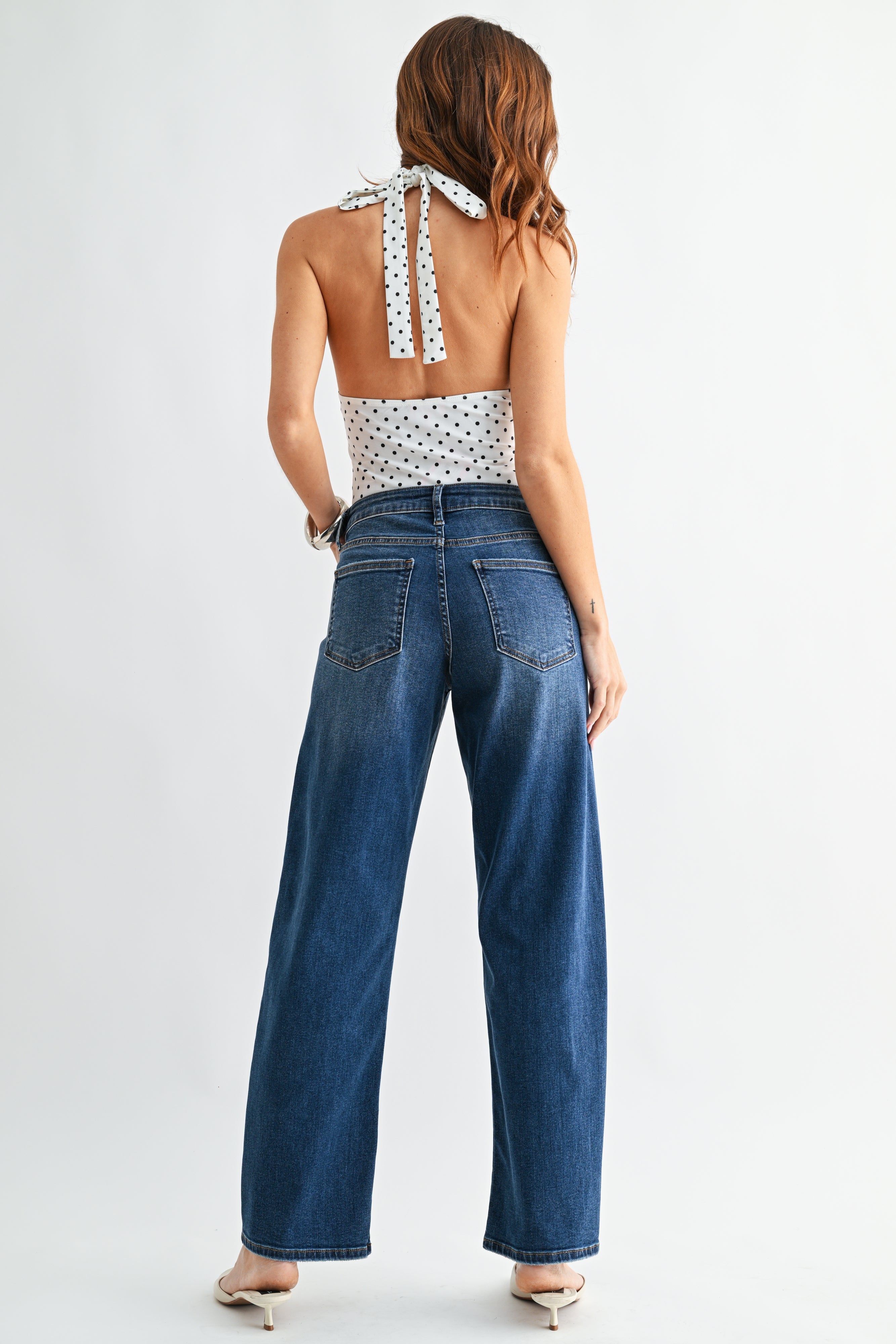 Woman wearing a white patterned top and blue jeans on a white background
