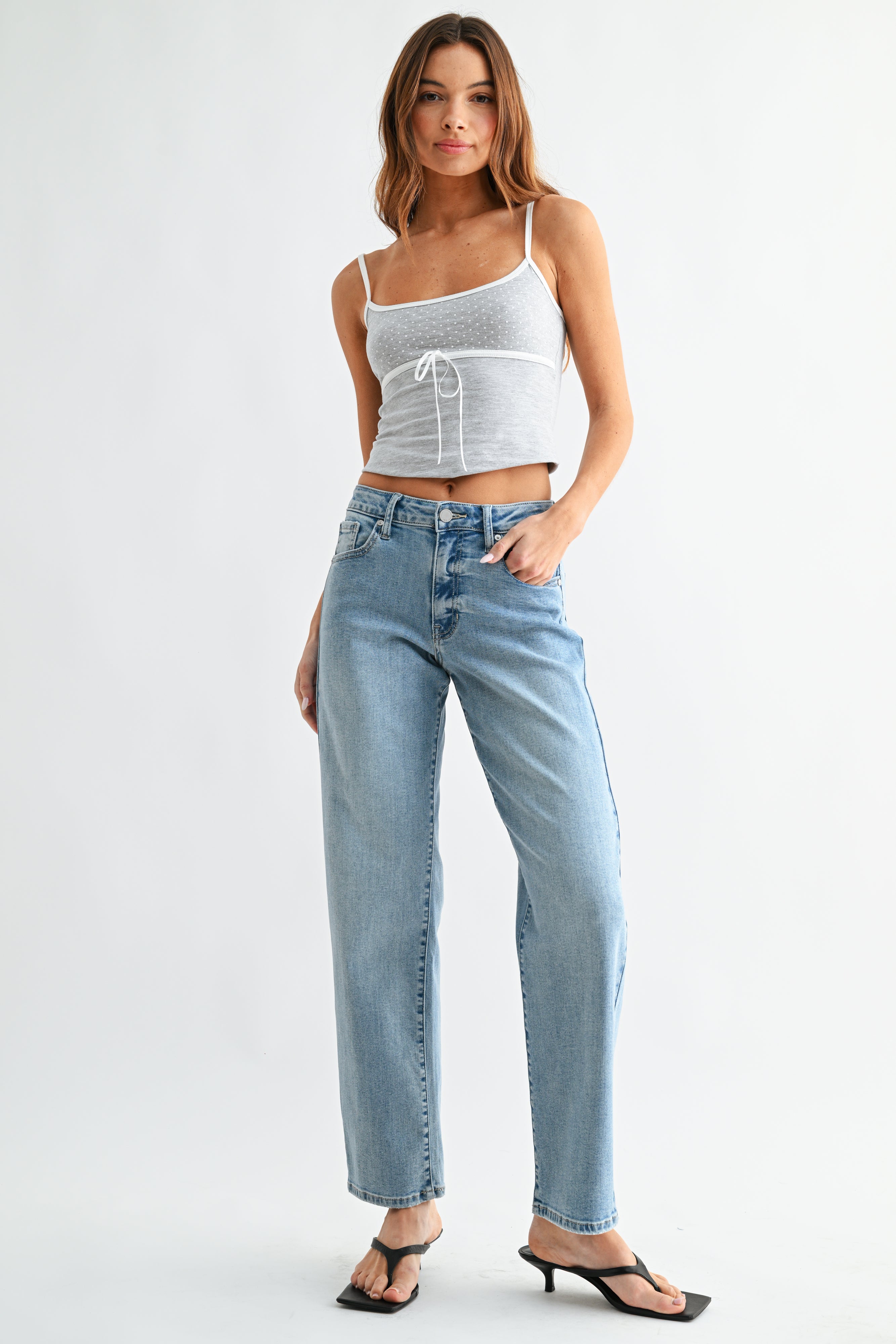 Woman wearing a white crop top and light blue jeans on a white background
