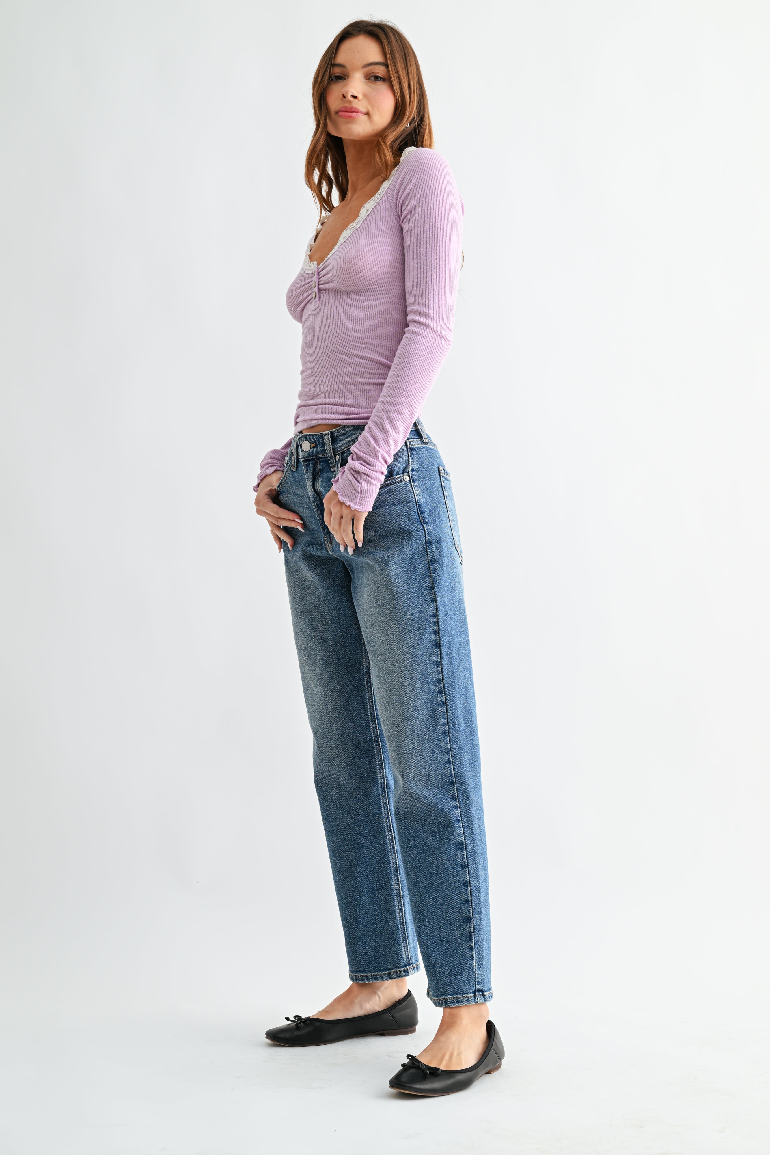 Woman wearing a pink top and blue jeans on a white background