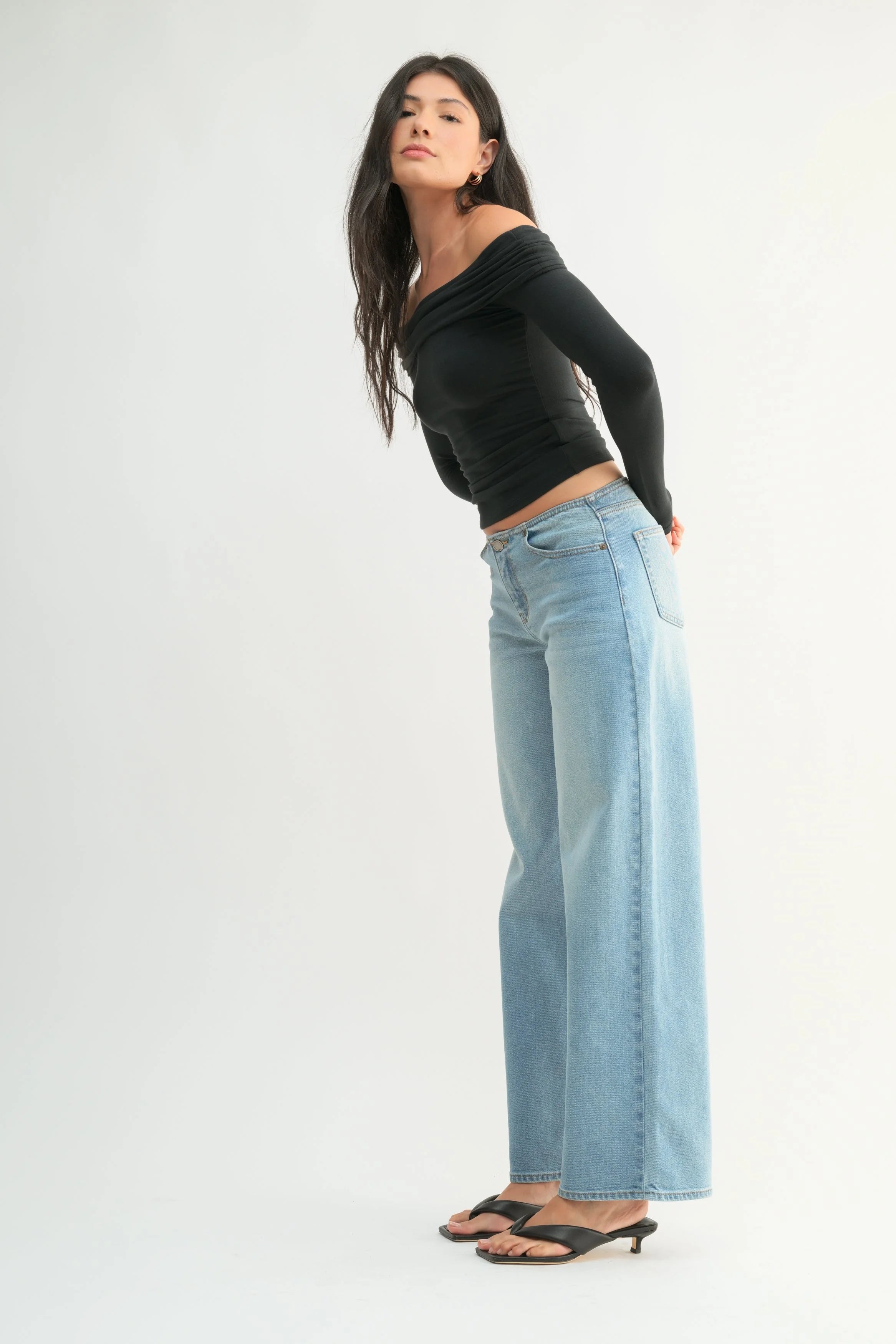 Woman wearing a black top and light blue jeans on a white background