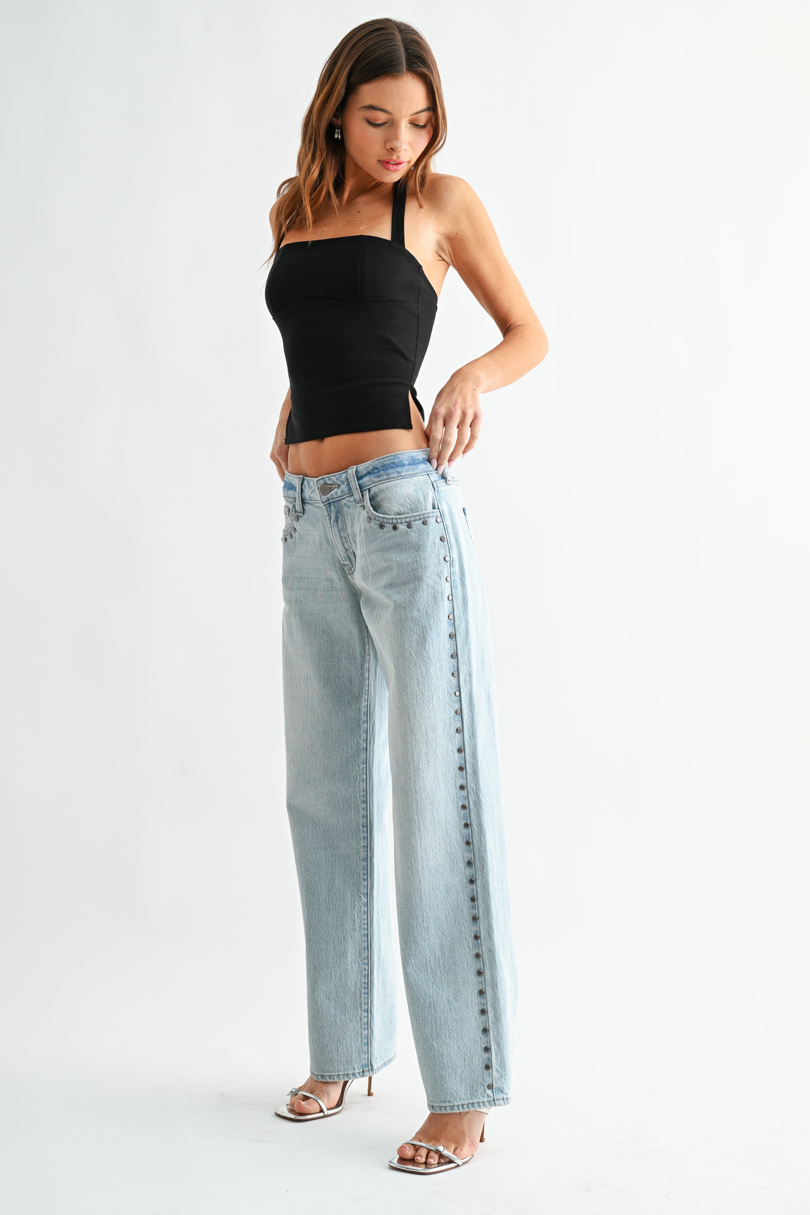 Woman wearing a black top and light blue jeans on a white background