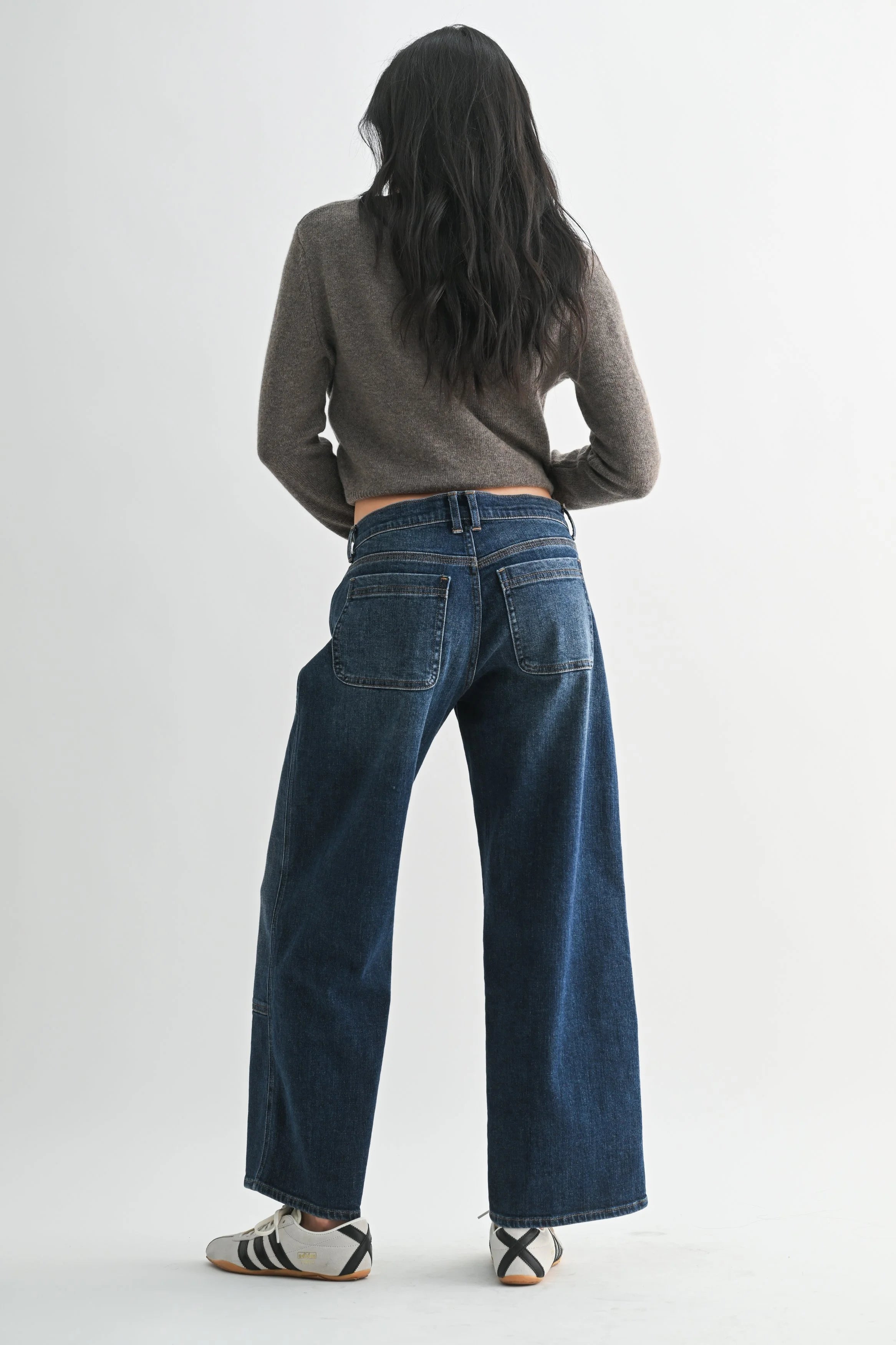 Person wearing blue jeans and a gray sweater on a white background