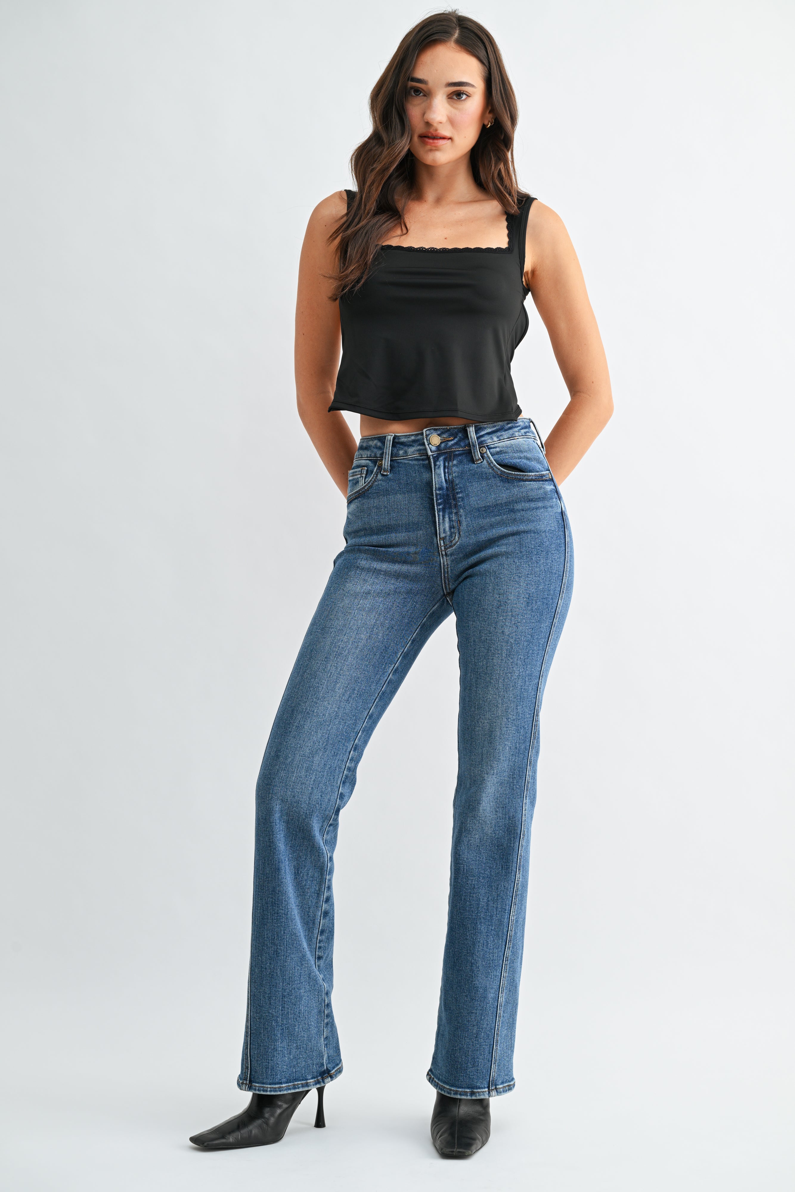 Woman wearing blue jeans and a black top on a white background