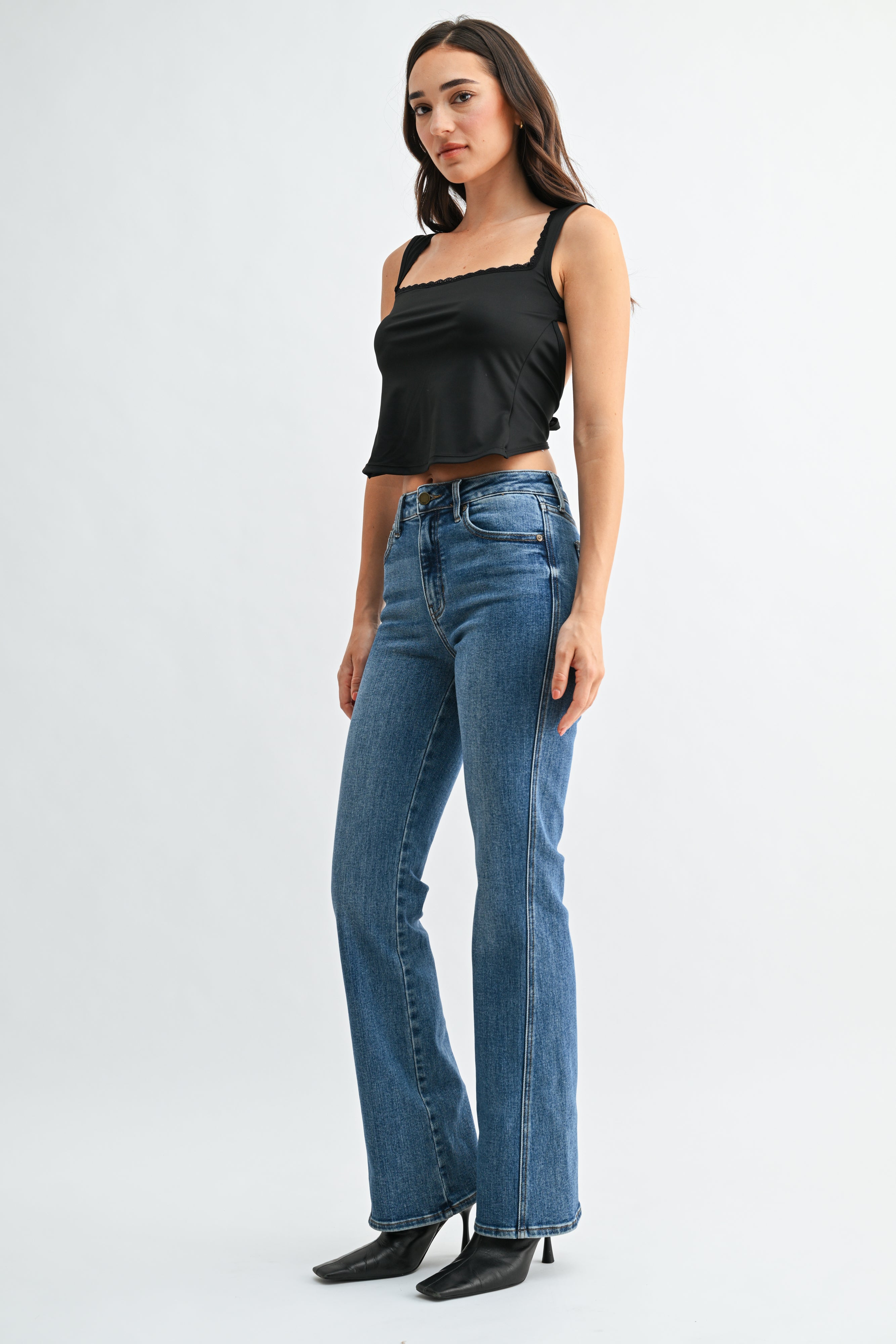 Woman wearing a black top and blue jeans on a white background
