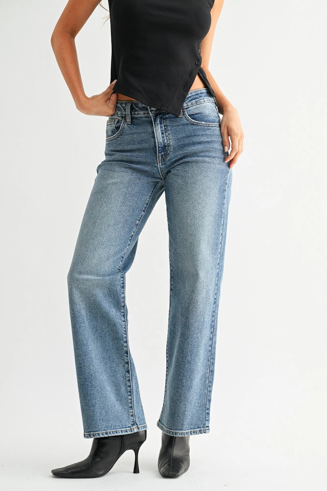 Woman wearing blue jeans and a black top on a white background