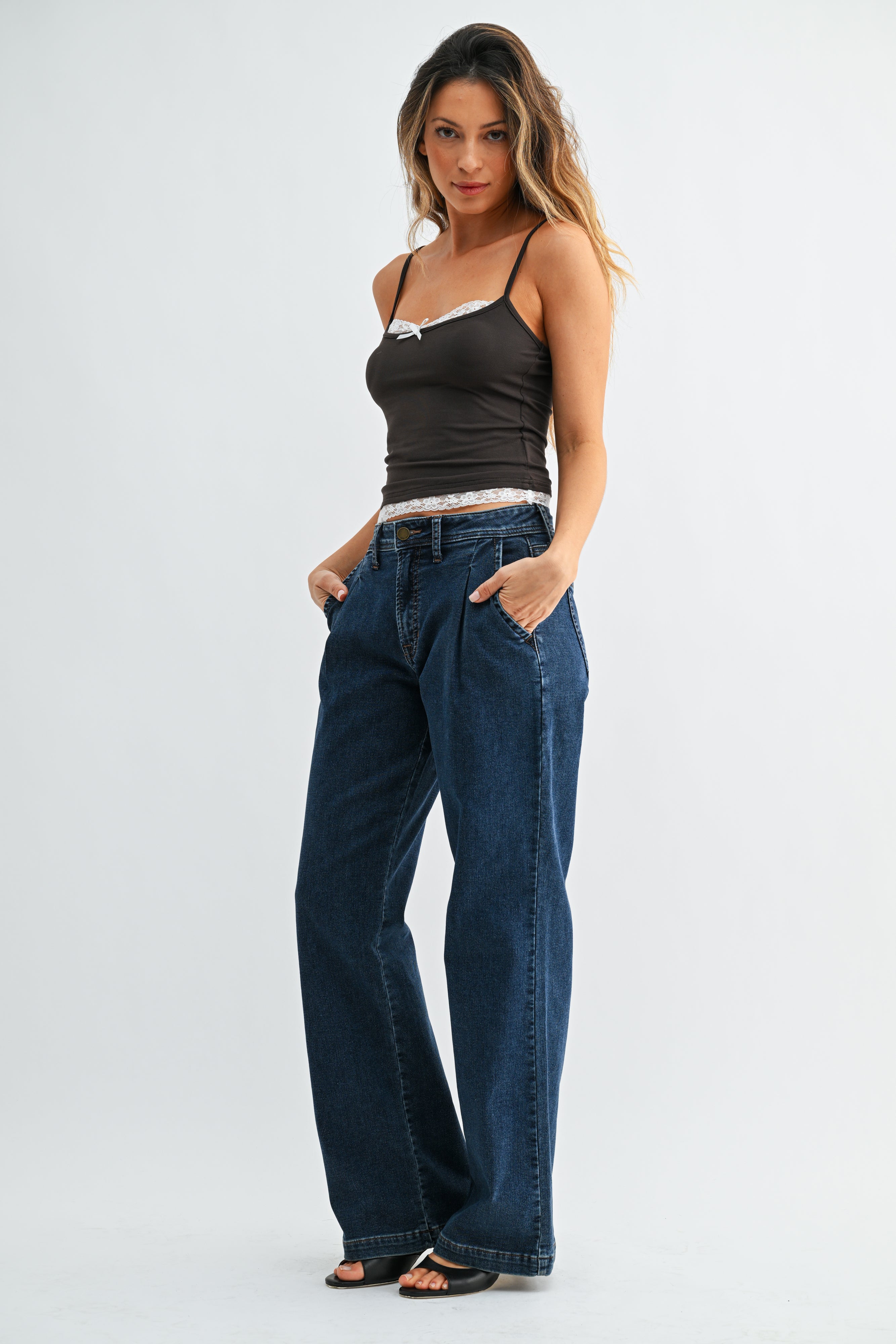 Woman wearing a black tank top and blue jeans on a white background