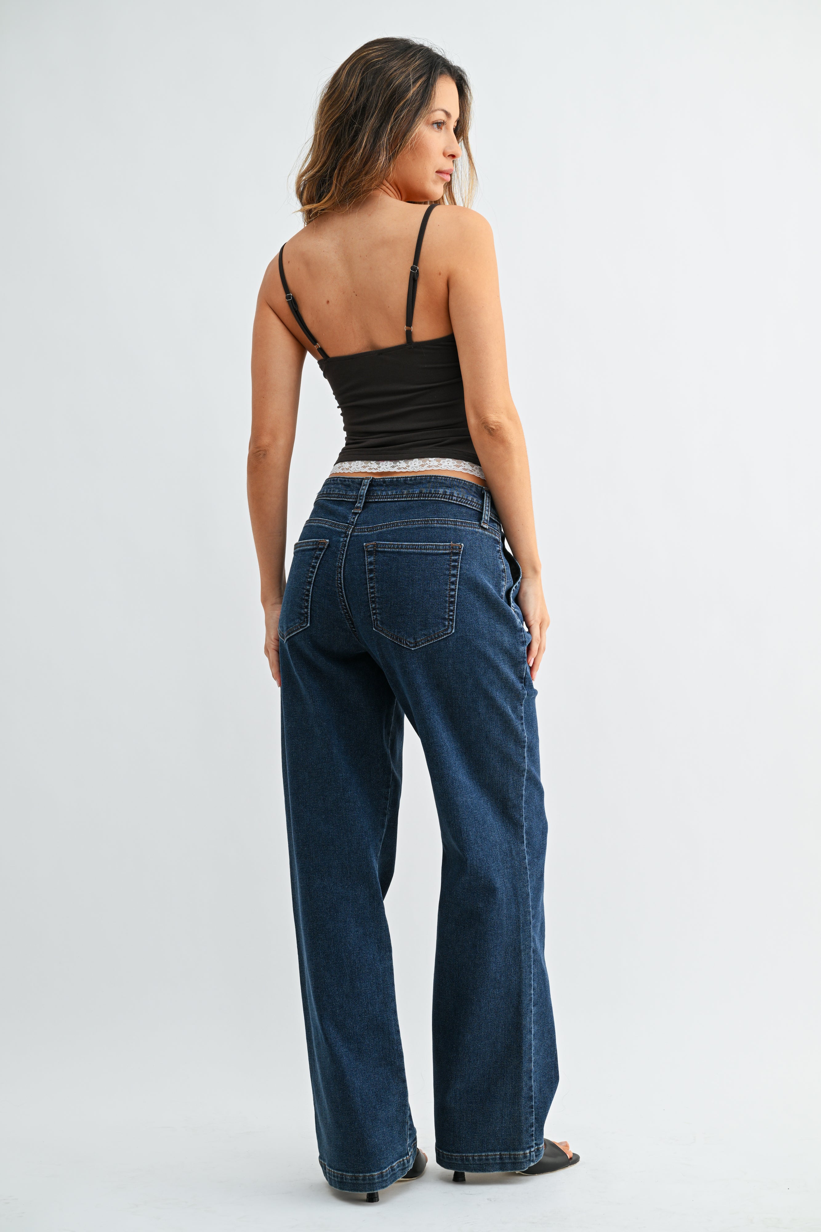 Woman wearing blue jeans and a black top on a white background