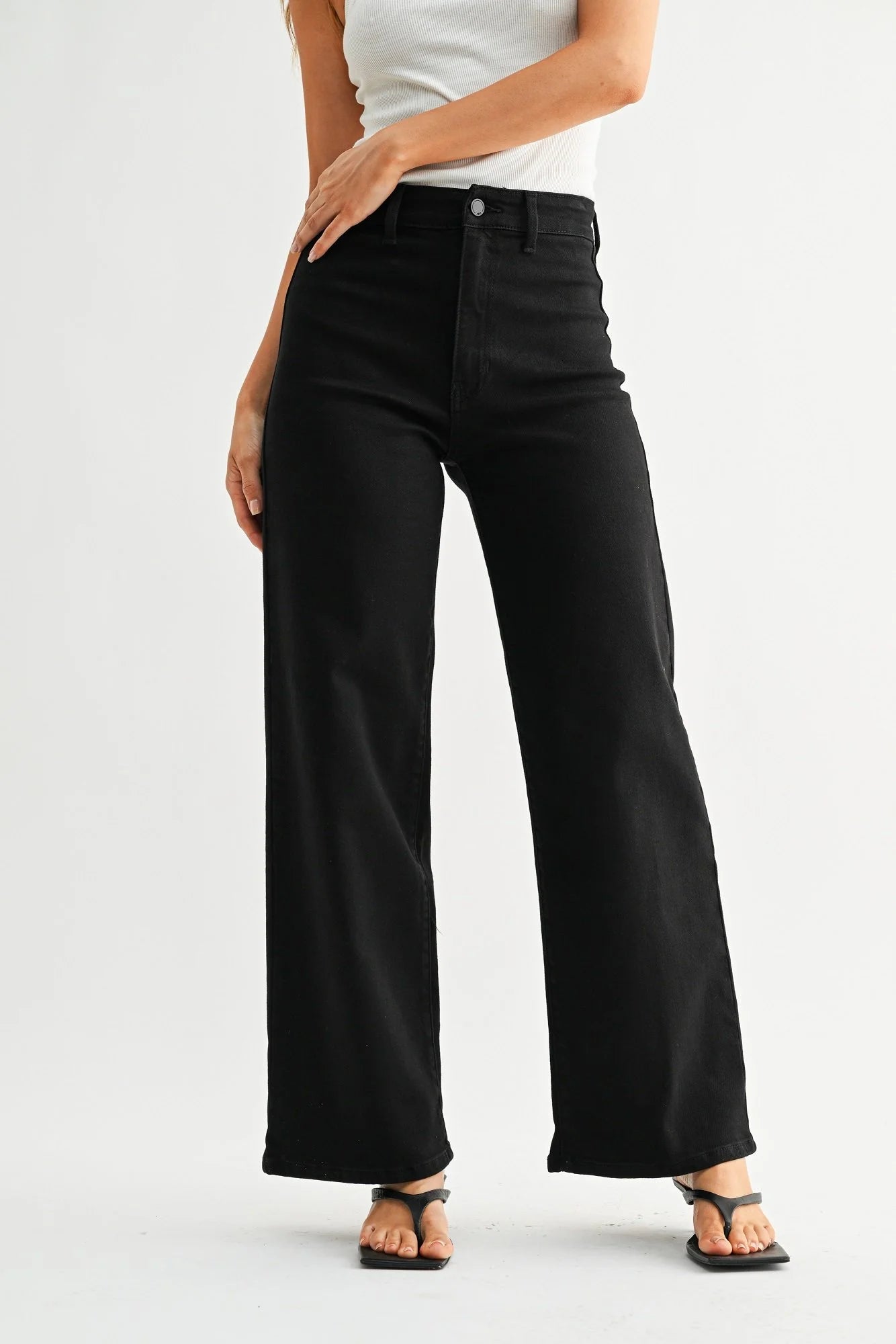 Person wearing black wide-leg jeans on a white background