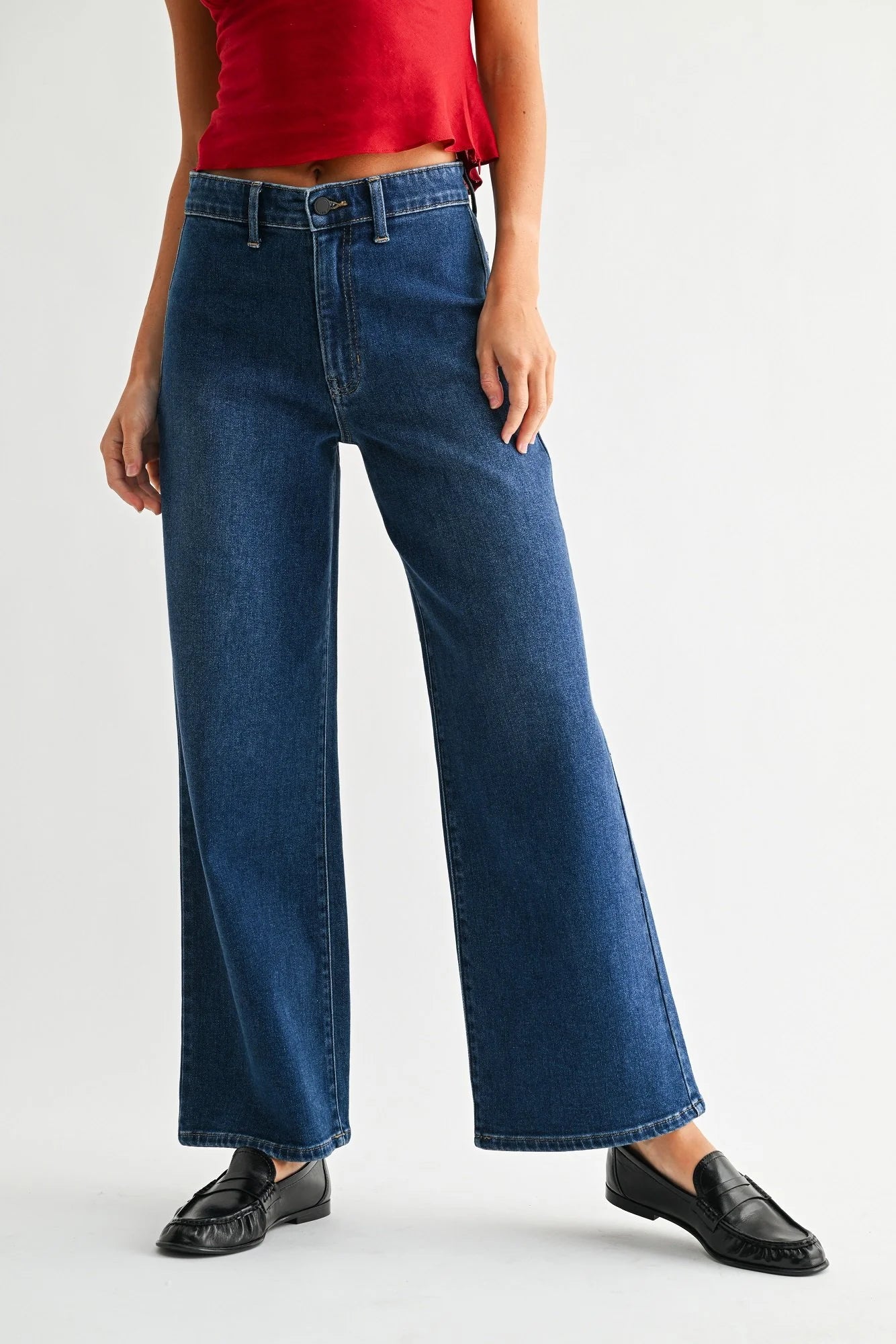 Person wearing blue jeans and a red top on a white background