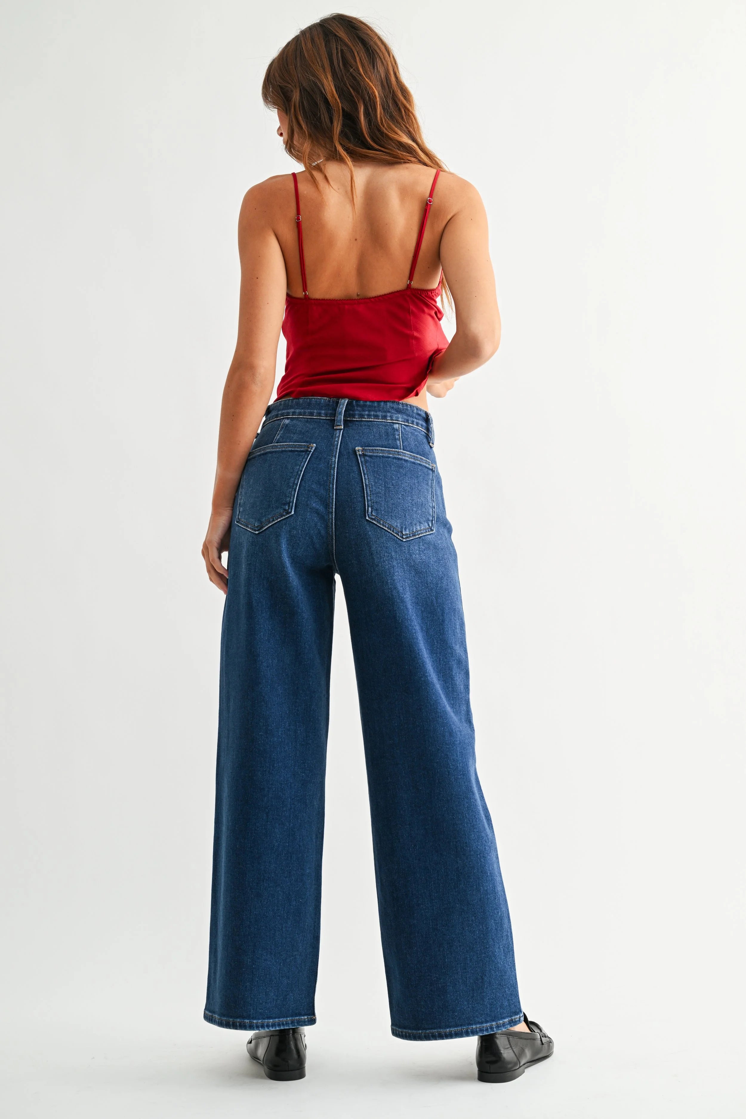 Woman wearing a red top and blue jeans on a white background