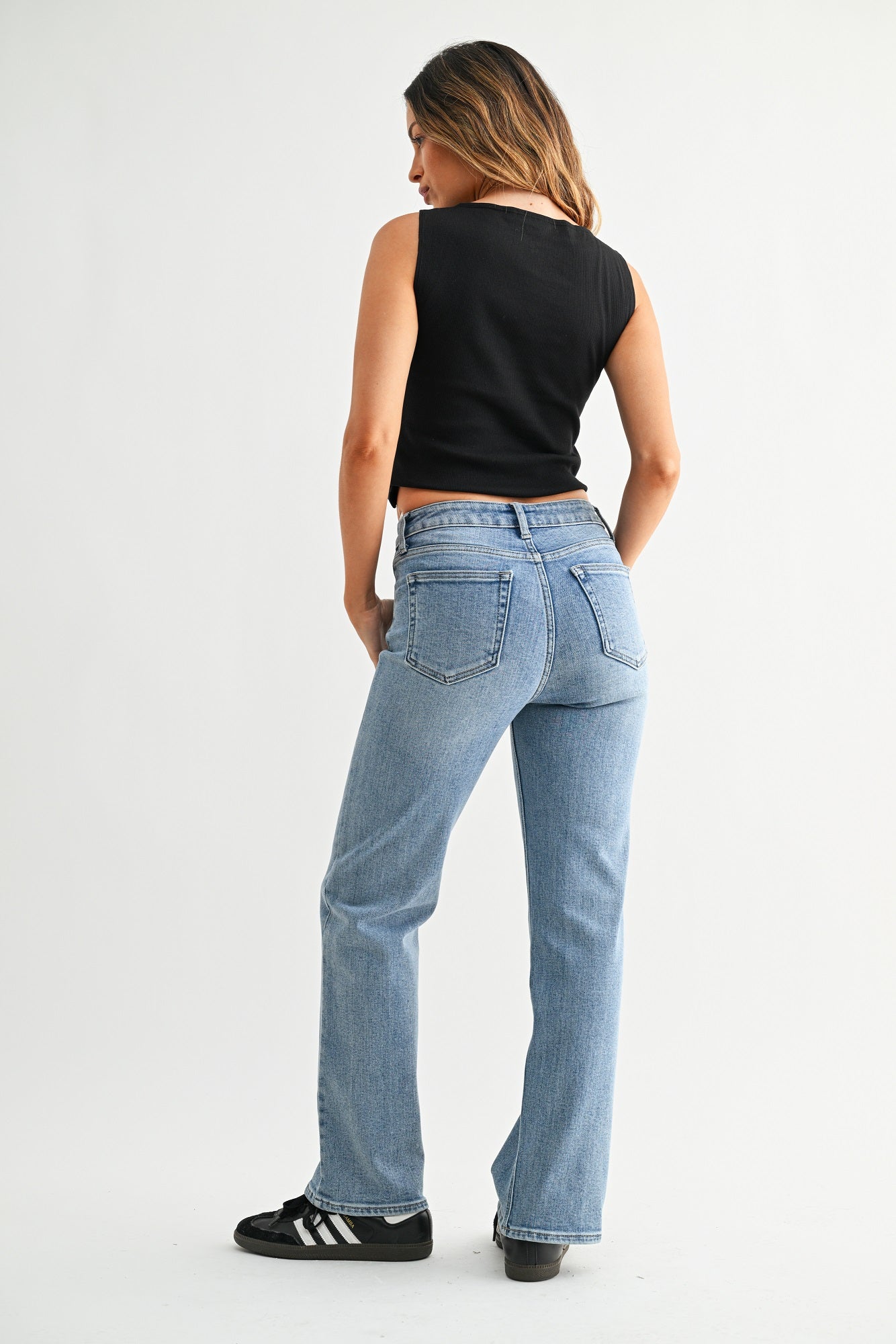 Person wearing light blue jeans and a black top on a white background