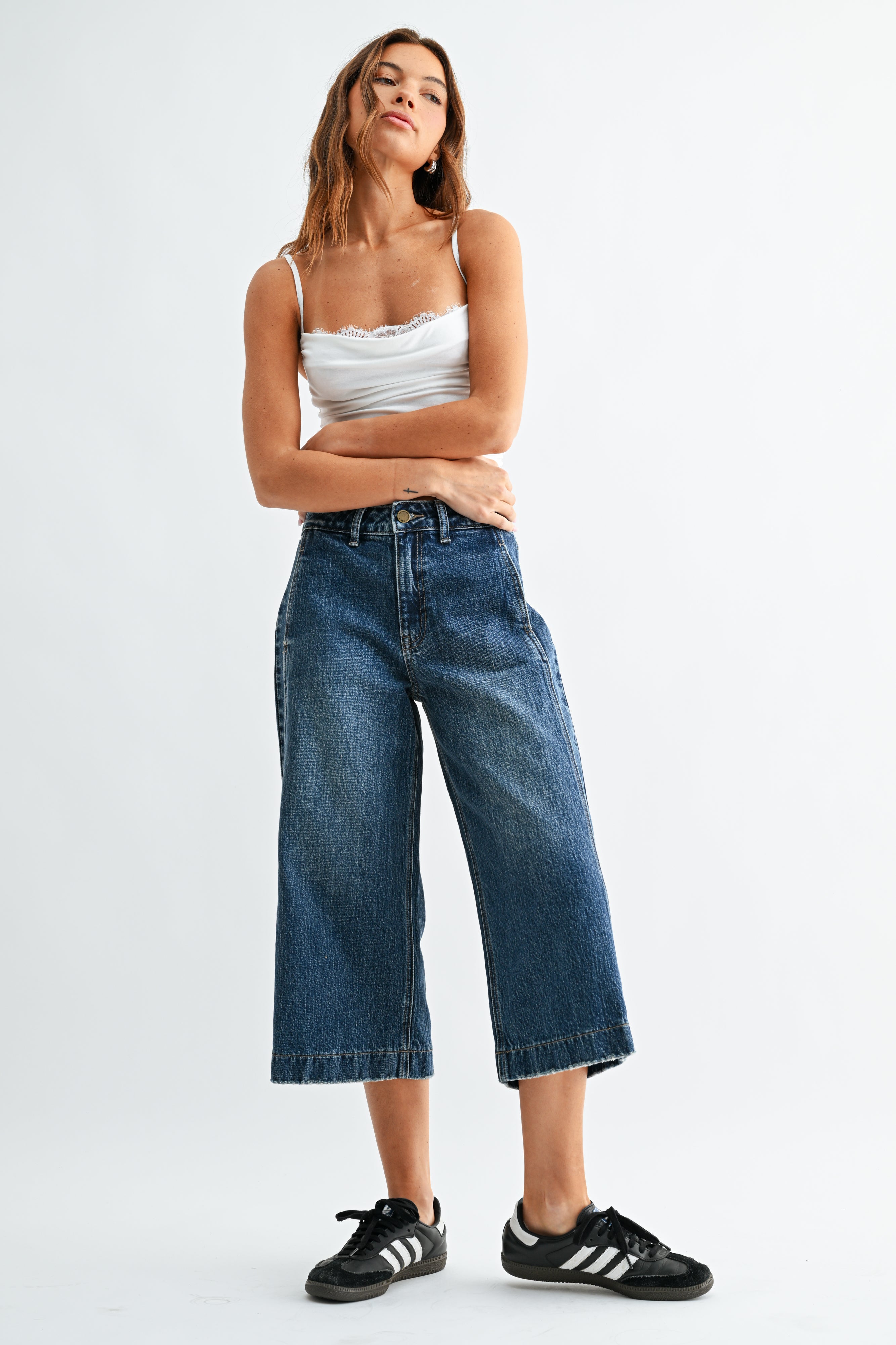 Woman wearing a white top and blue jeans on a white background