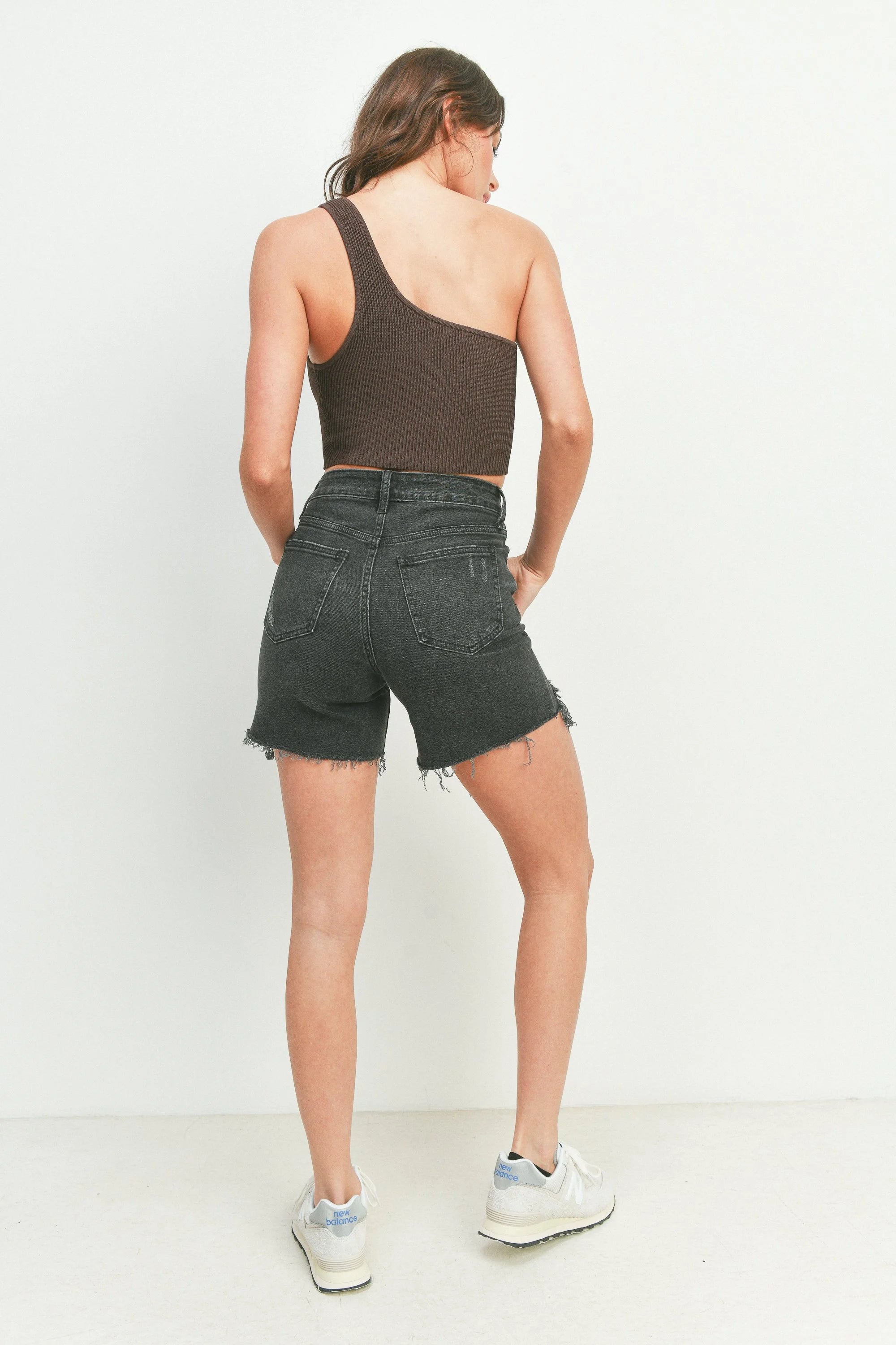Person wearing a brown tank top and black denim shorts on a white background