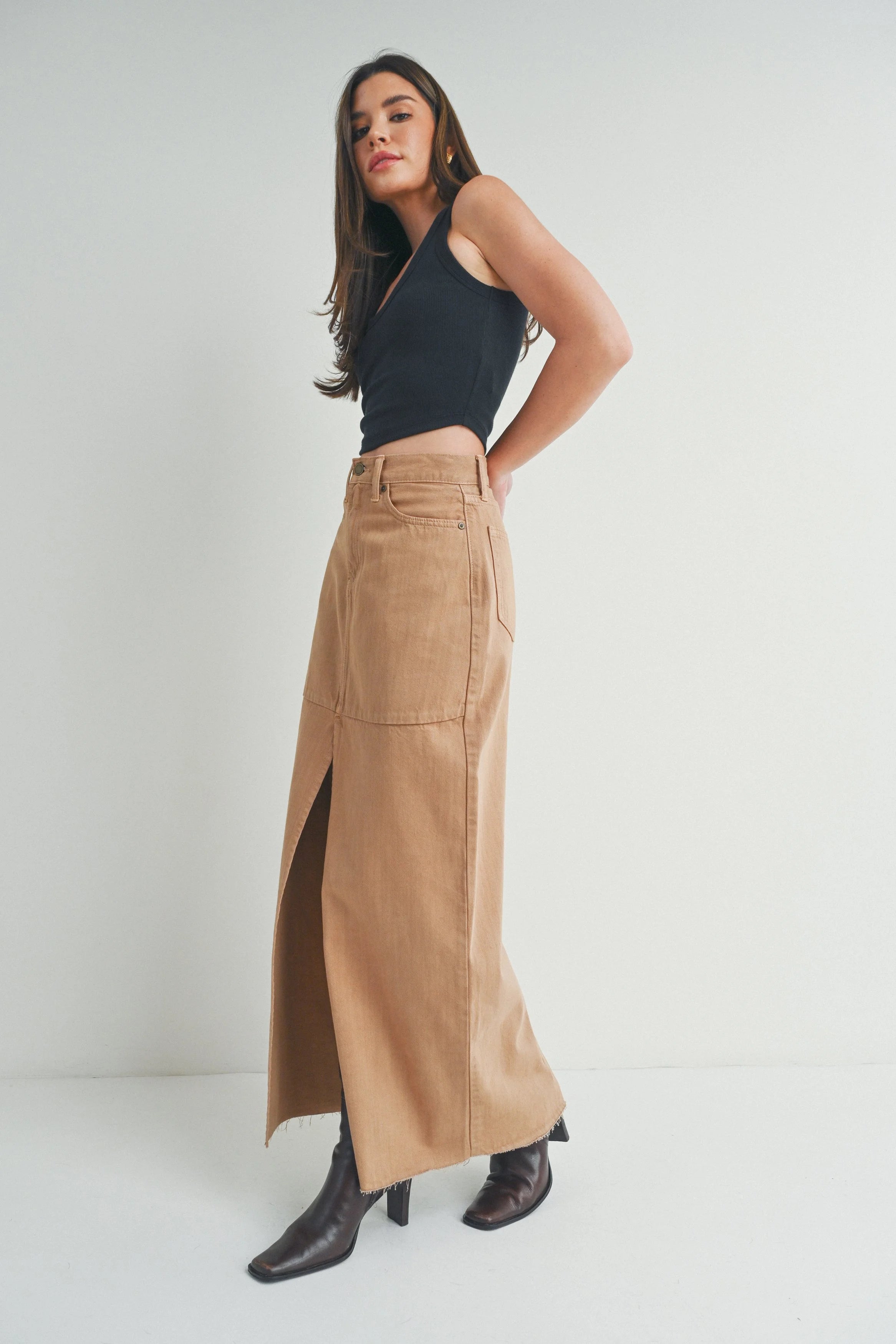 Woman wearing a black top and tan skirt on a white background