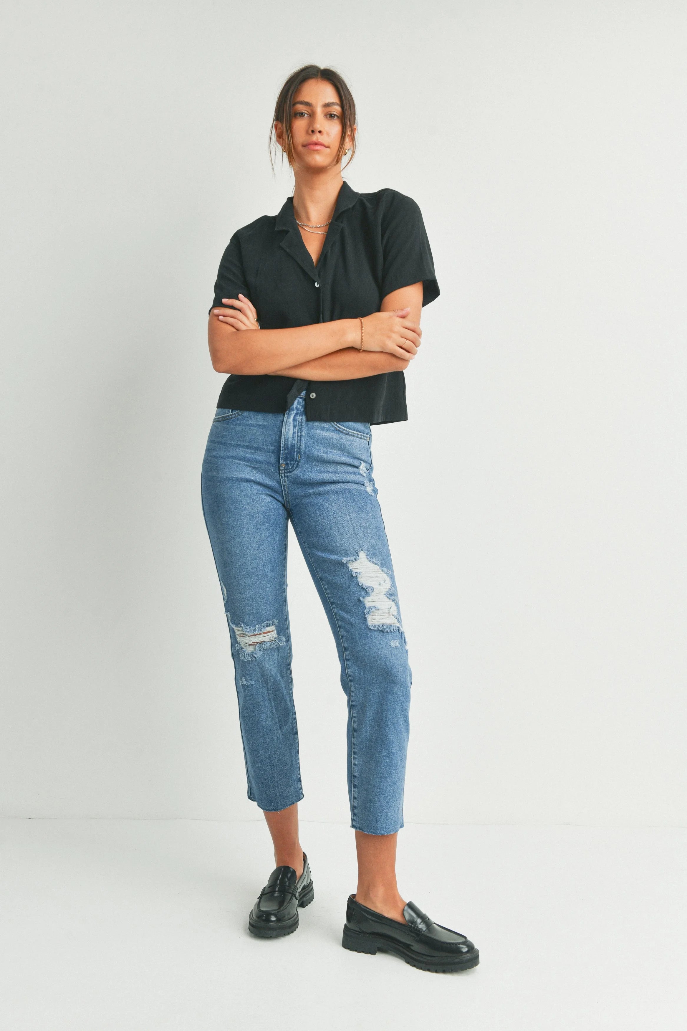 Woman wearing a black shirt and blue jeans with a white background