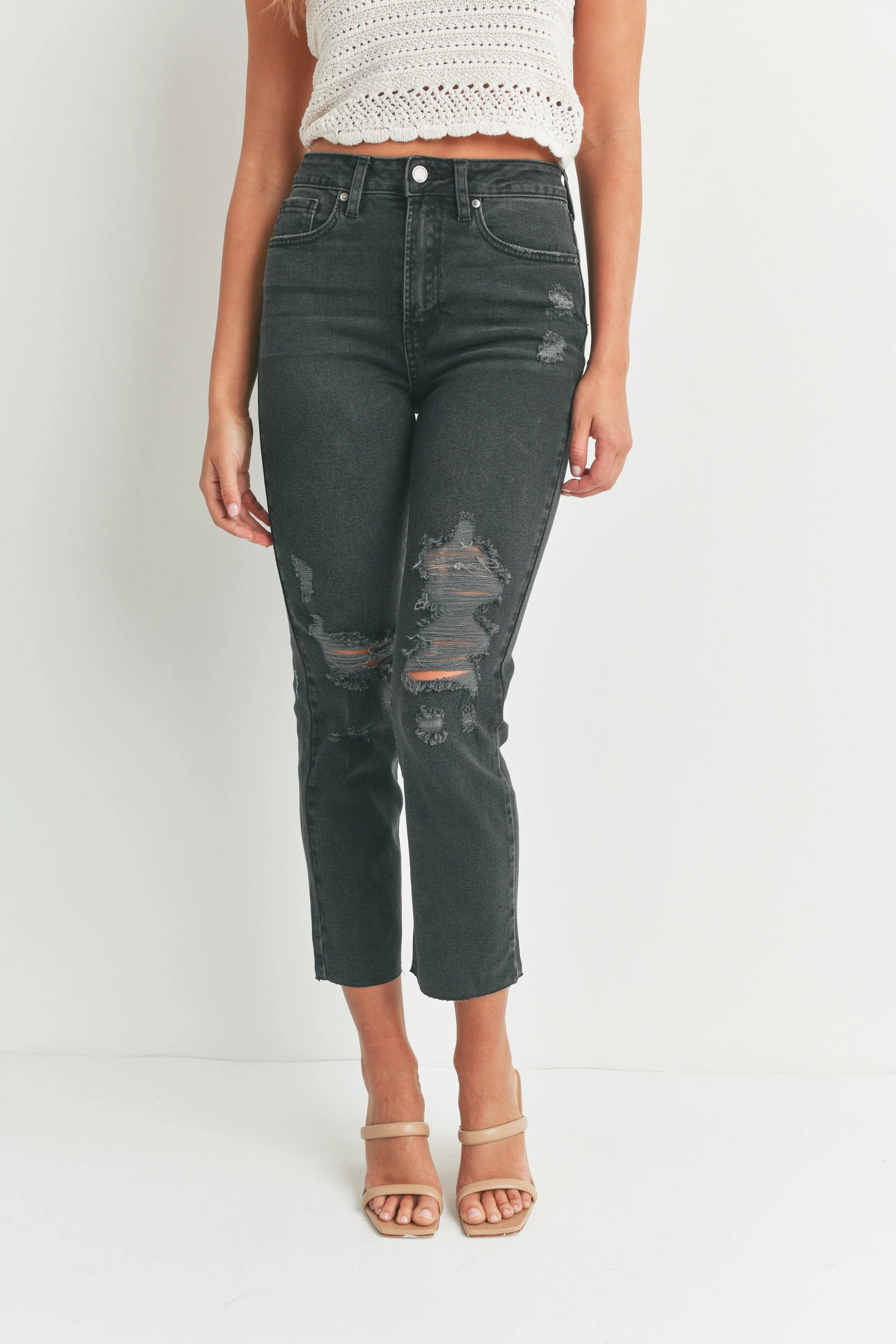 Person wearing distressed black jeans on a white background
