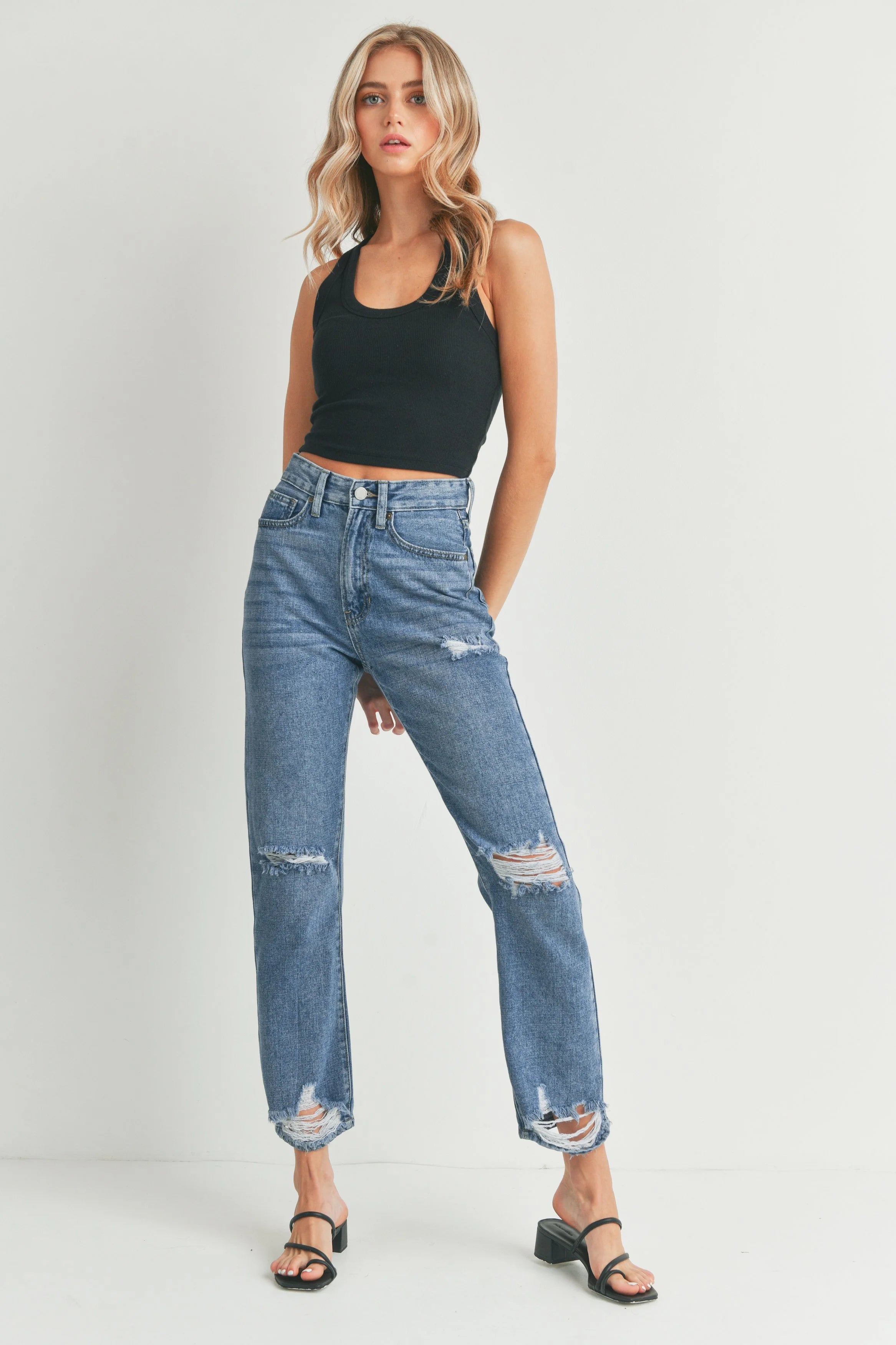 Woman wearing blue jeans and a black top on a white background