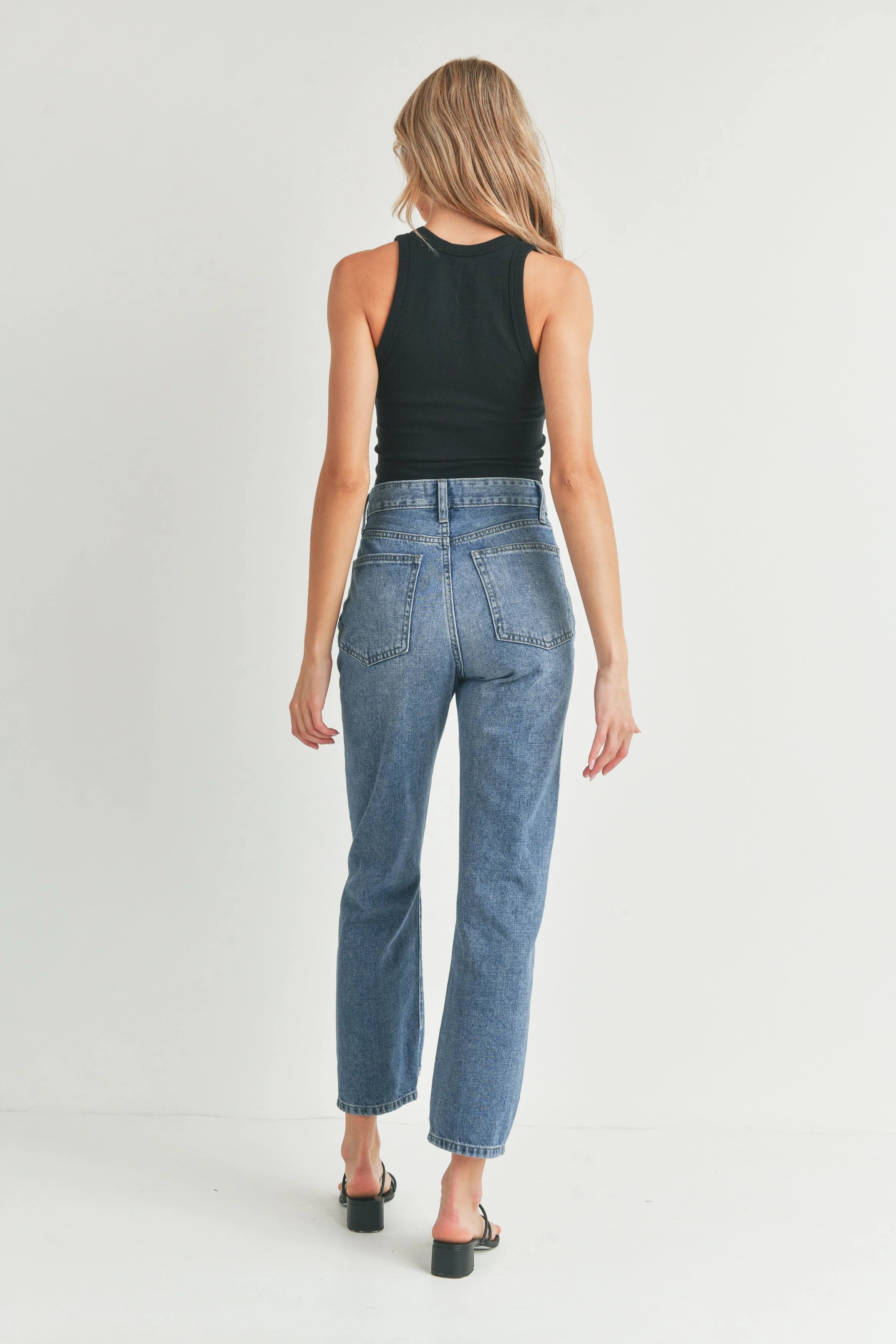 Woman wearing blue jeans and a black top on a white background