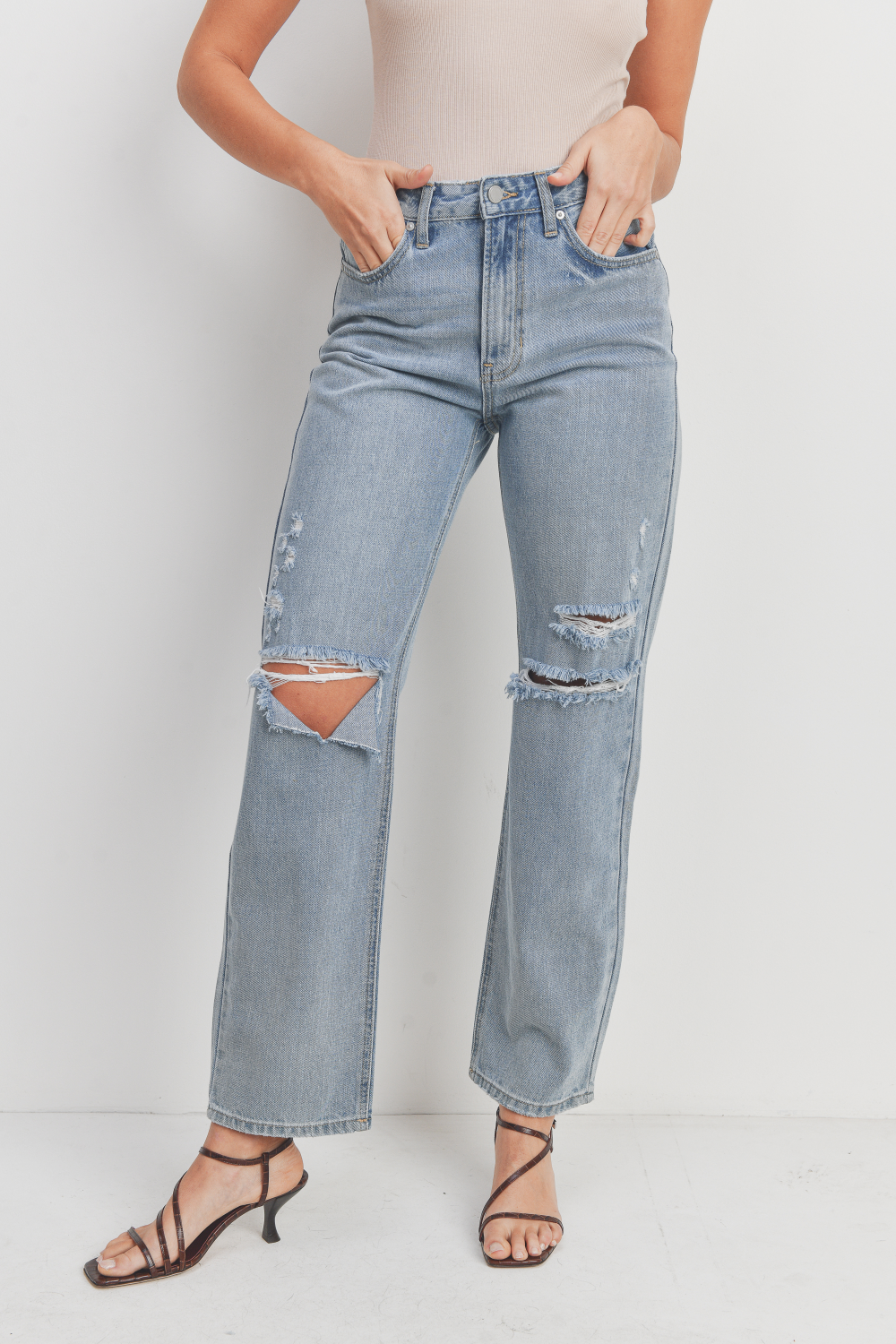 Person wearing light blue jeans with a patch on a white background