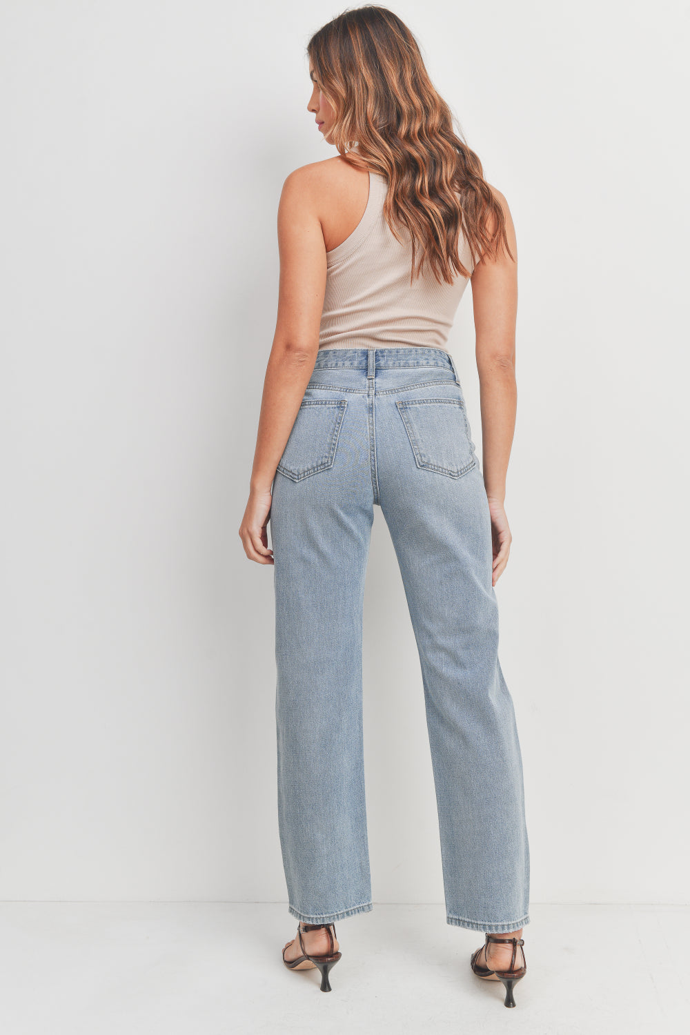Woman wearing light blue jeans on a white background