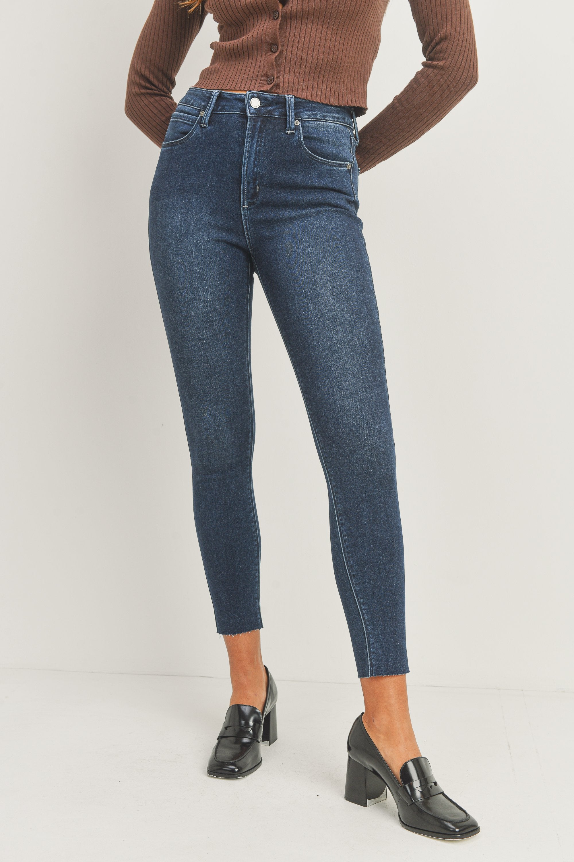 Person wearing blue jeans and black shoes on a white background