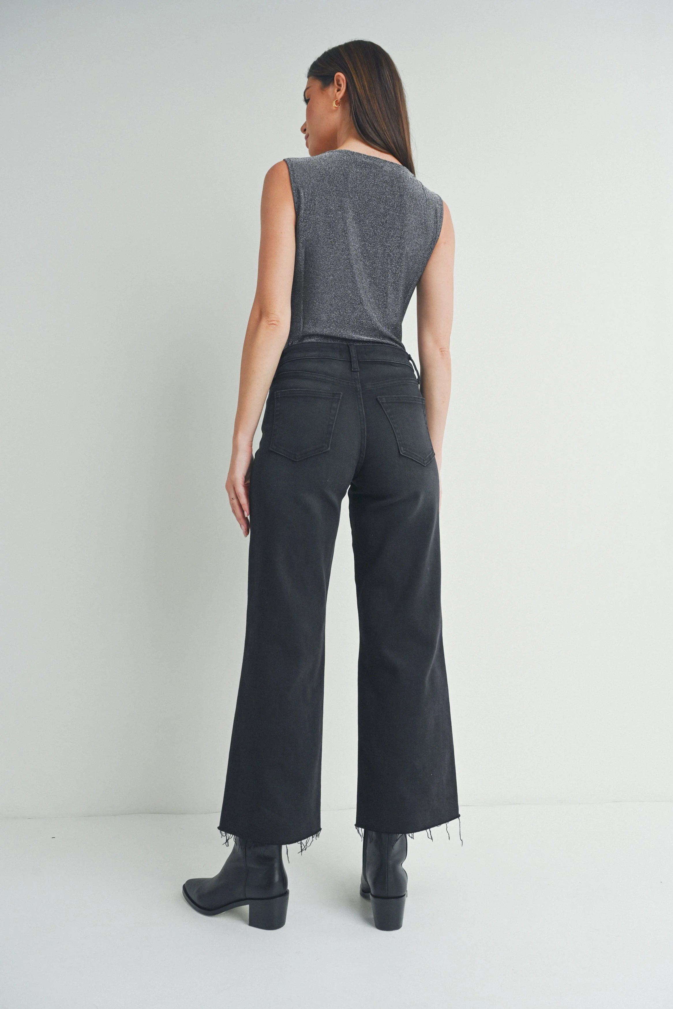 Woman wearing a sleeveless gray top and black wide-leg pants on a white background