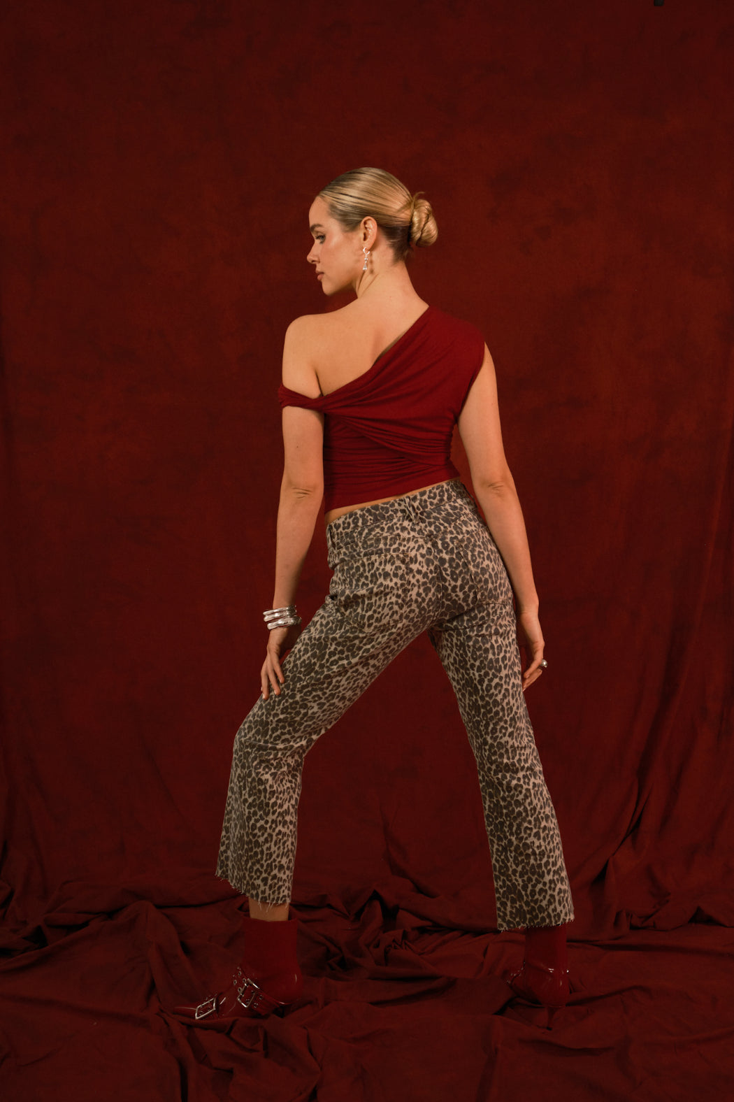 Woman wearing a red top and patterned pants against a maroon background